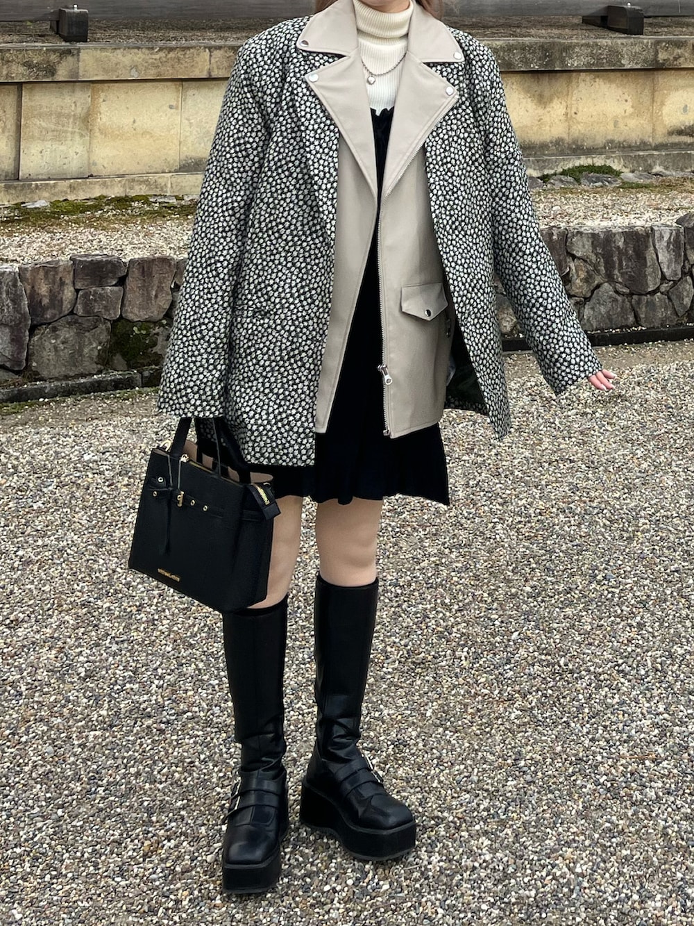 ホワイト系のニット/セーター、ブラック系のテーラードジャケット、ホワイト系のライダースジャケットを着用したレディースの春コーディネートの2枚目の写真