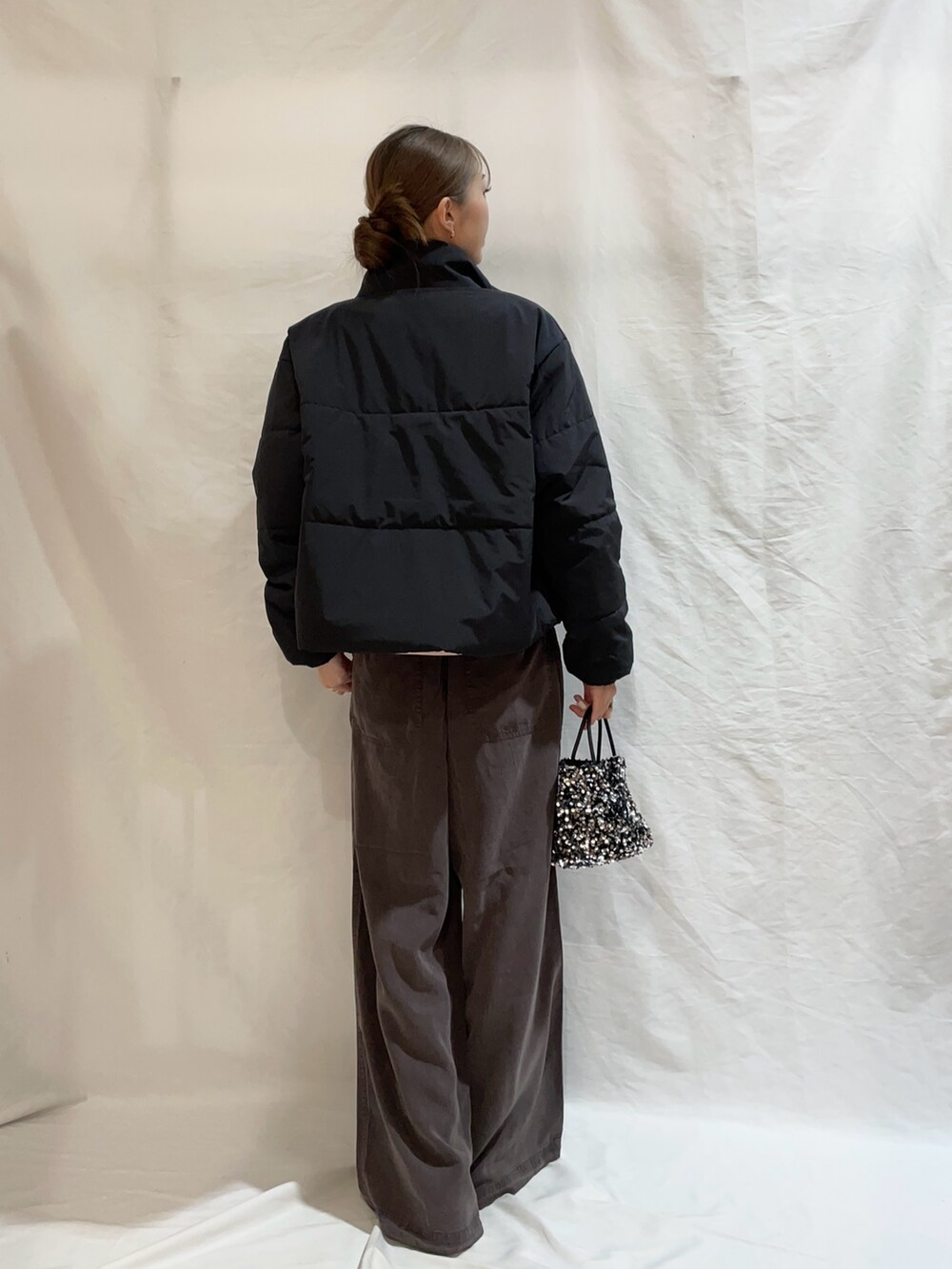 ピンク系のニット/セーター、ブラック系のダウンジャケット/コート、シルバー系のショルダーバッグを着用したレディースの秋コーディネートの4枚目の写真