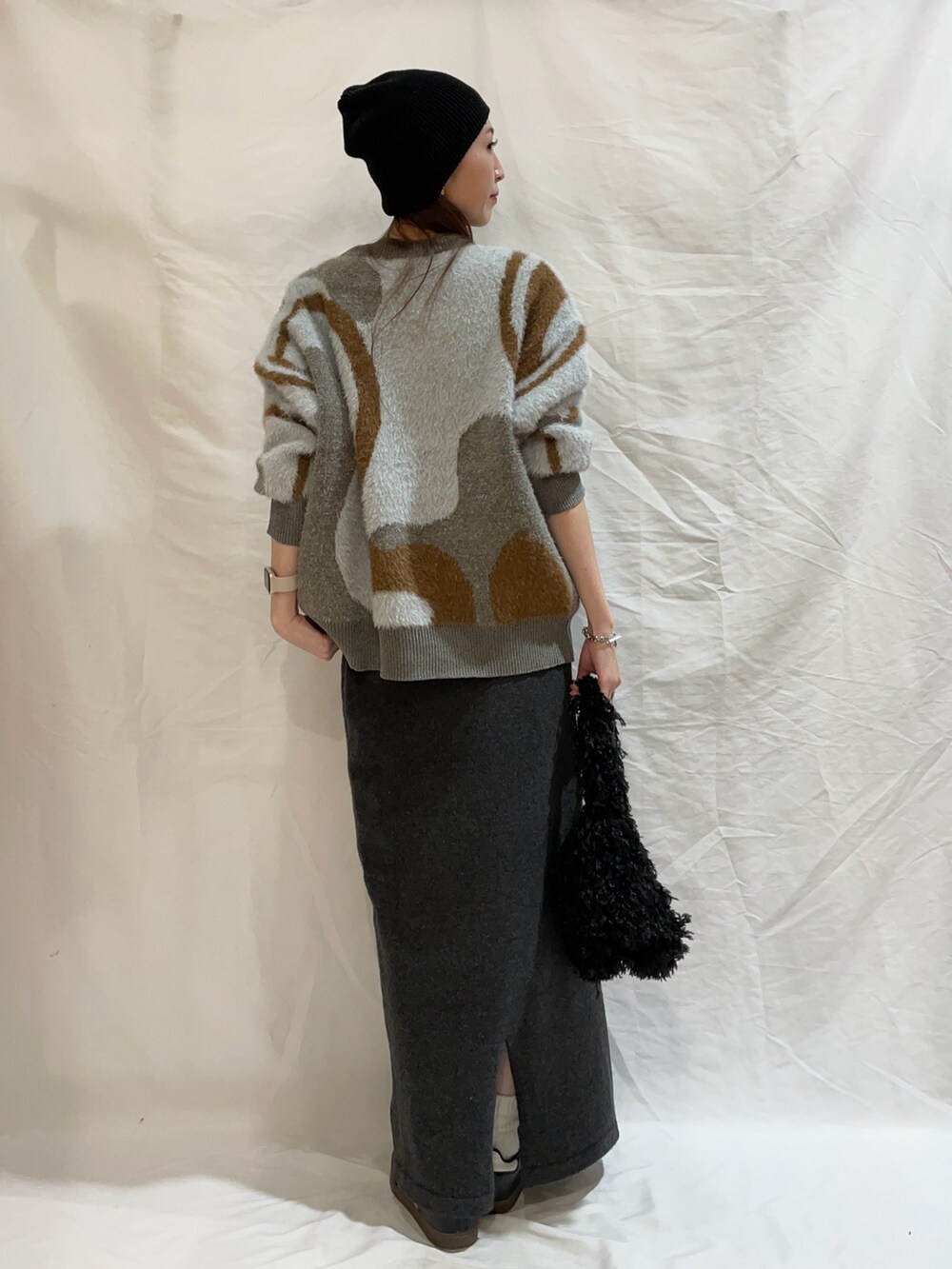 グレー系のスカート、ブルー系のニット/セーター、ブラック系のショルダーバッグを着用したレディースの秋コーディネートの3枚目の写真