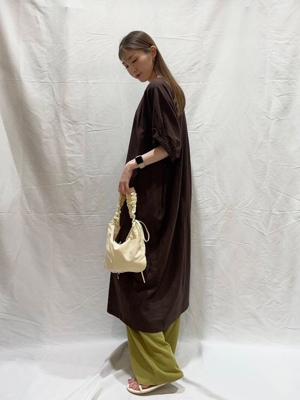 ホワイト系のサンダル、ブラウン系のワンピース、ホワイト系のハンドバッグを着用したレディースの春コーディネートの2枚目の写真