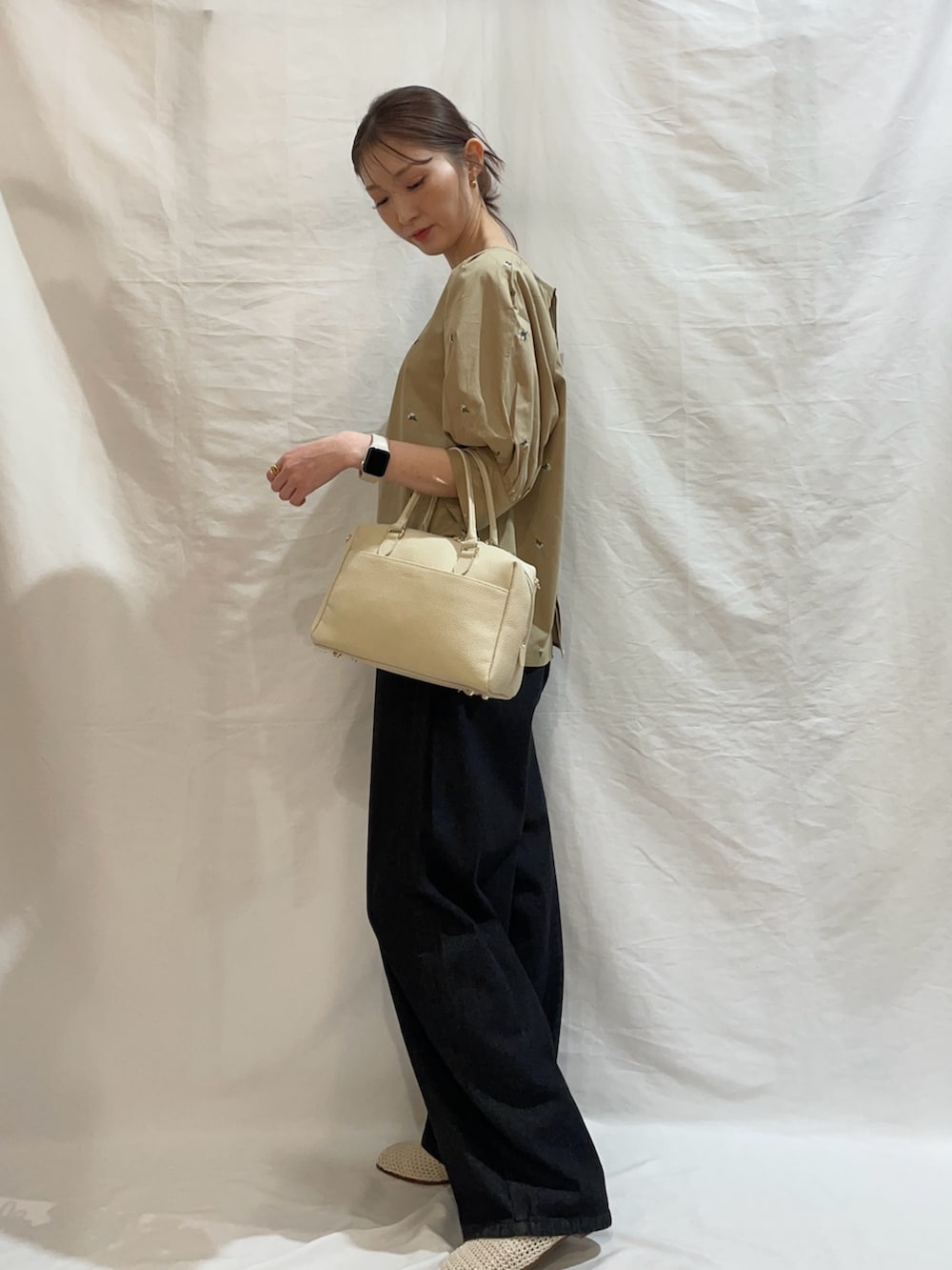 ブラック系のデニムパンツ、ベージュ系のシャツ/ブラウスを着用したレディースの春コーディネートの3枚目の写真