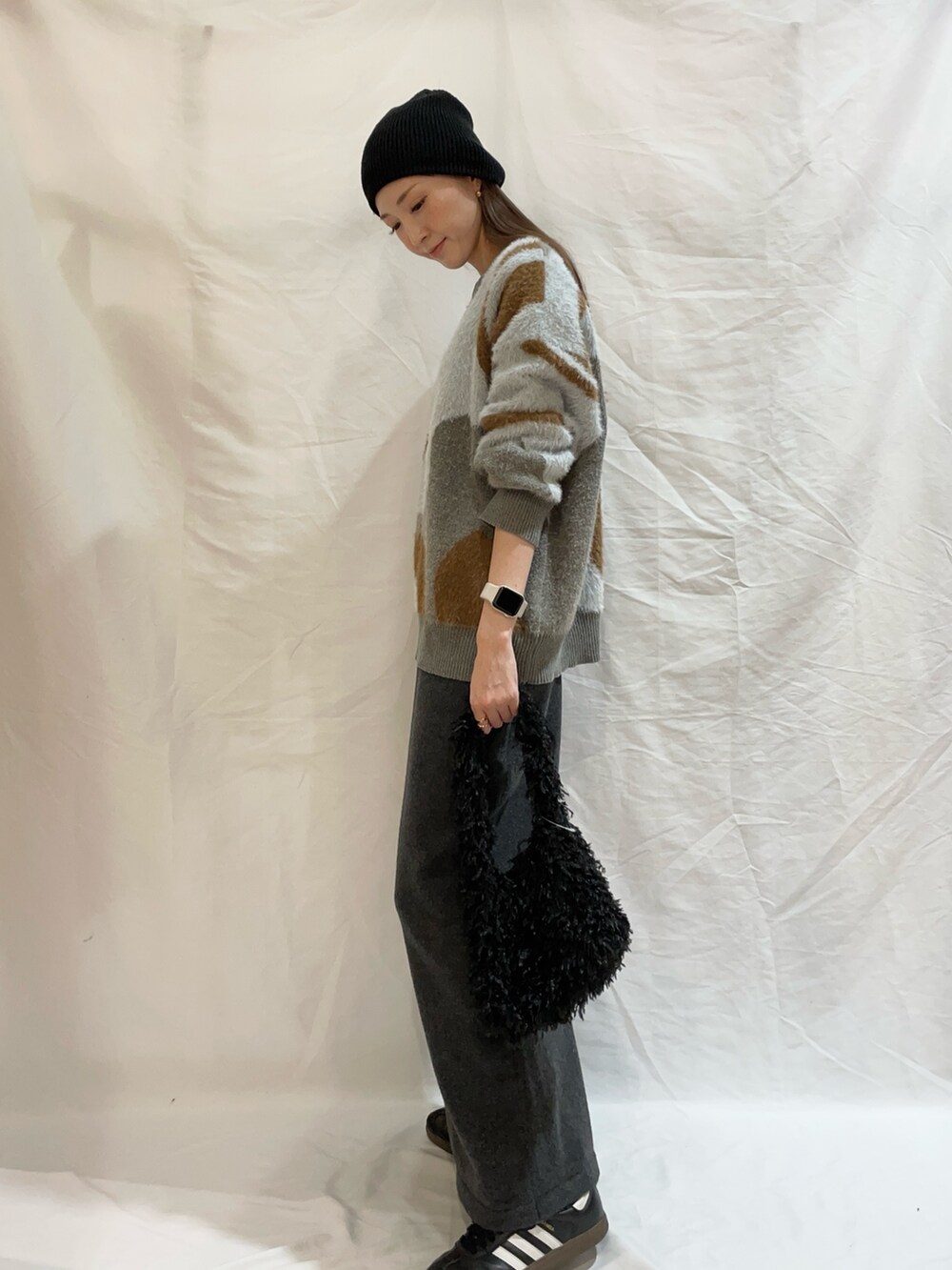 グレー系のスカート、ブルー系のニット/セーター、ブラック系のショルダーバッグを着用したレディースの秋コーディネートの2枚目の写真