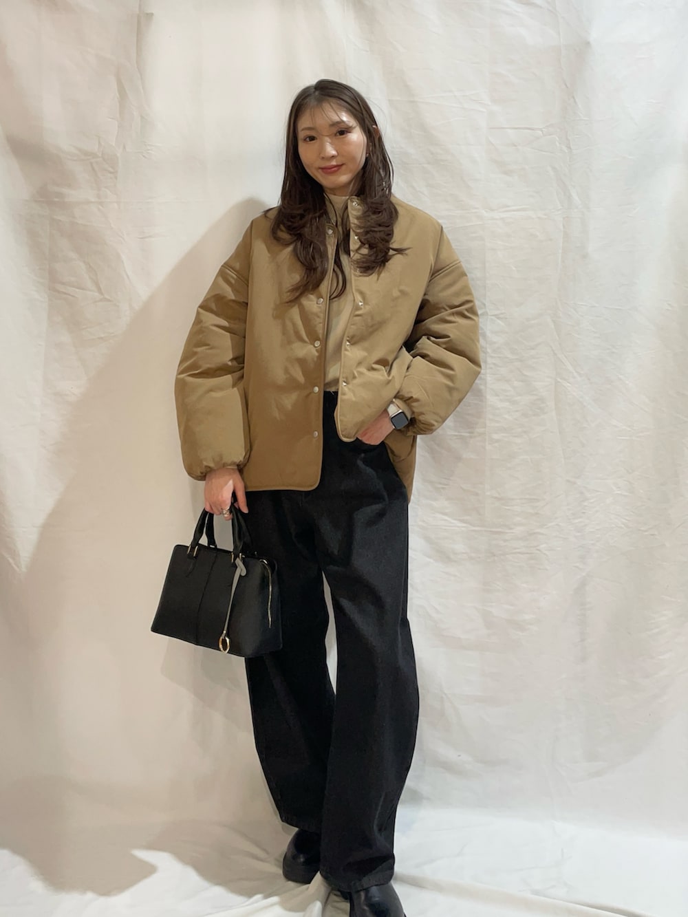 ホワイト系のニット/セーター、イエロー系のダウンジャケット/コート、ブラック系のデニムパンツを着用したレディースの冬コーディネートの3枚目の写真