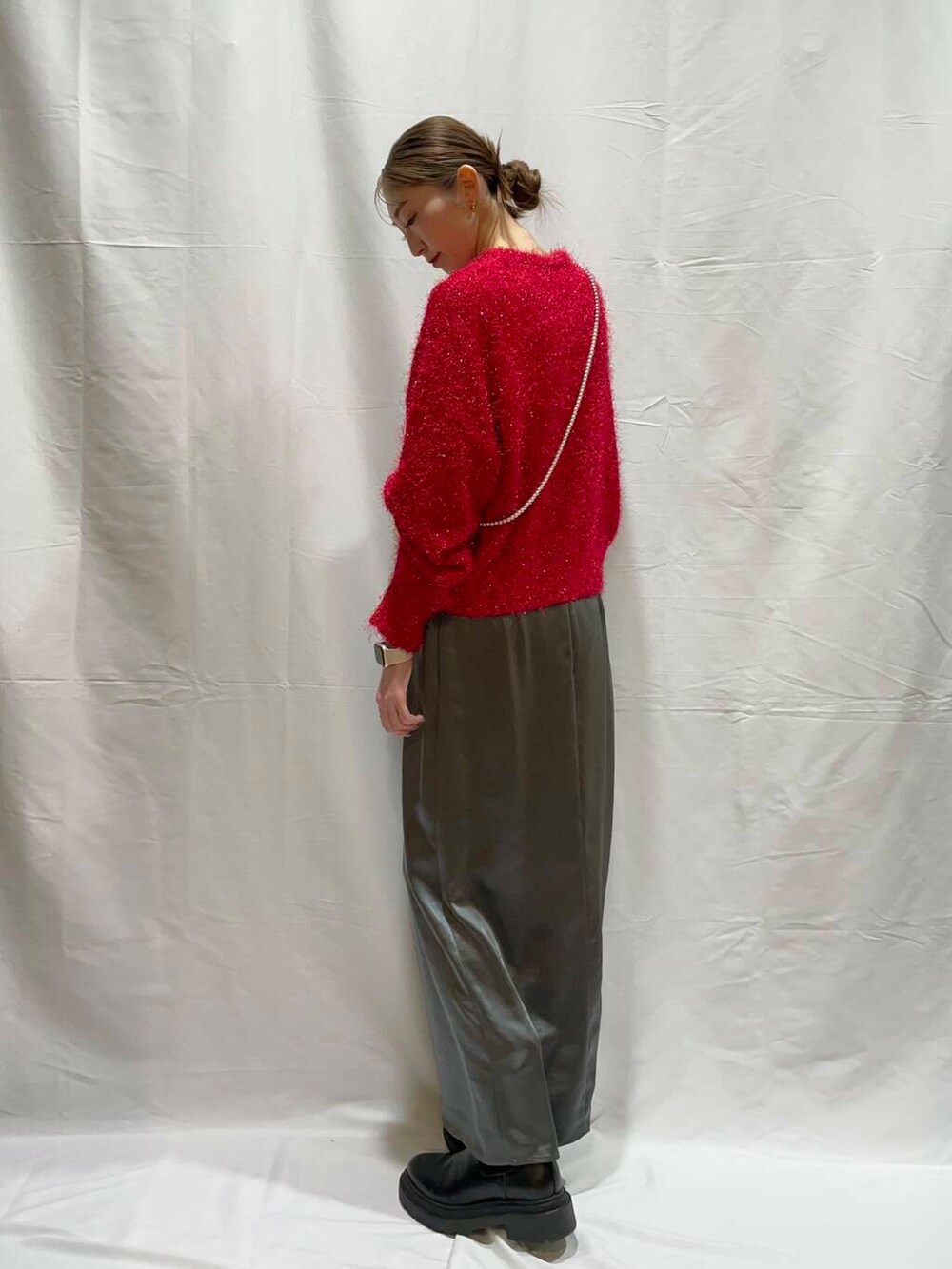 グレー系のスカート、レッド系のニット/セーターを着用したレディースの冬コーディネートの2枚目の写真