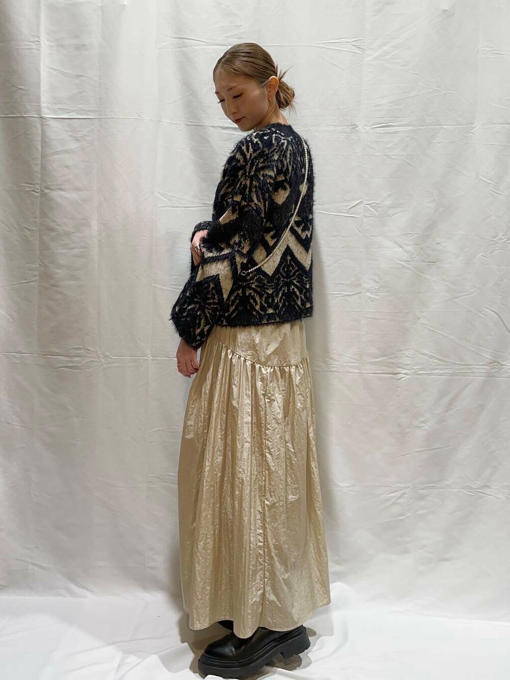 ベージュ系のスカート、ブラック系のニット/セーターを着用したレディースの冬コーディネートの2枚目の写真