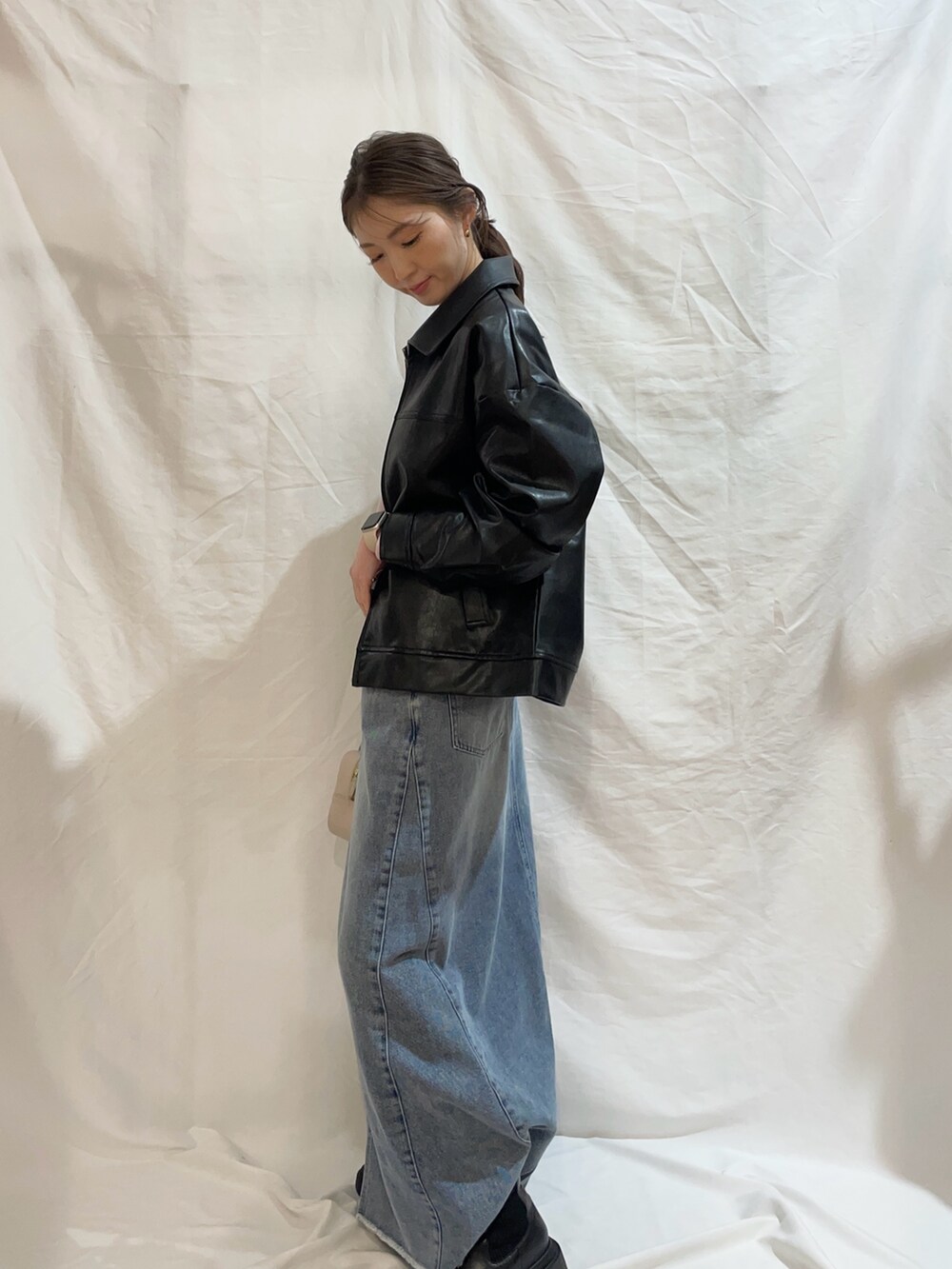 ブルー系のスカート、ピンク系のTシャツ/カットソー、ブラック系のブルゾンを着用したレディースの冬コーディネートの3枚目の写真