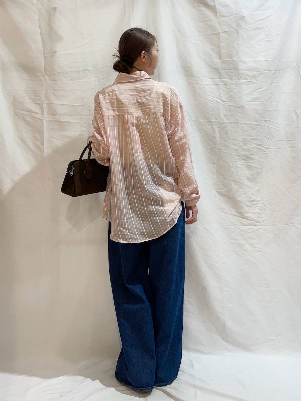 ブルー系のデニムパンツ、ブラウン系のボストンバッグ、ピンク系のシャツ/ブラウスを着用したレディースの夏コーディネートの3枚目の写真