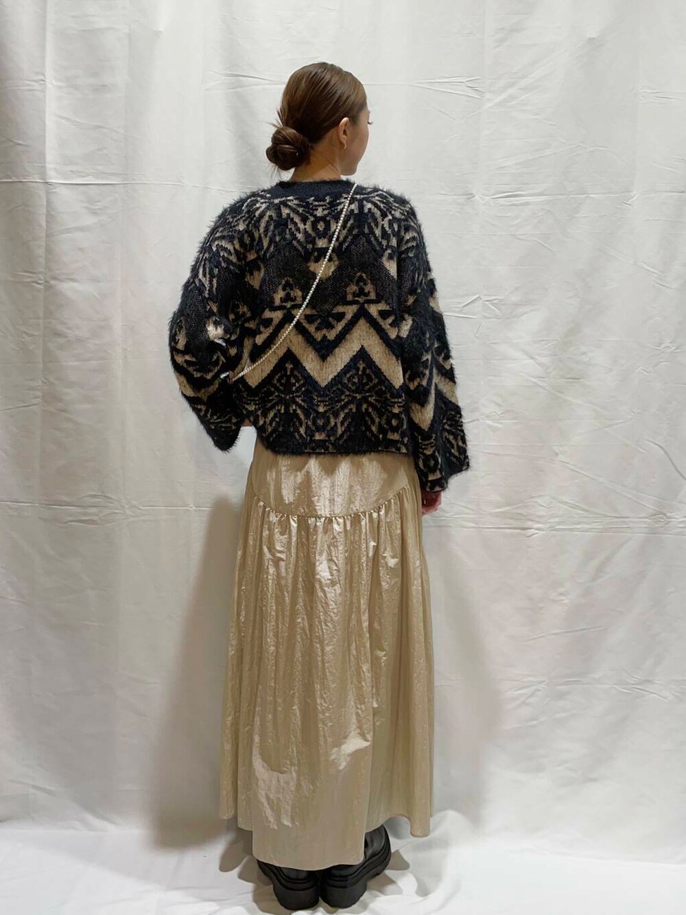 ベージュ系のスカート、ブラック系のニット/セーターを着用したレディースの冬コーディネートの4枚目の写真