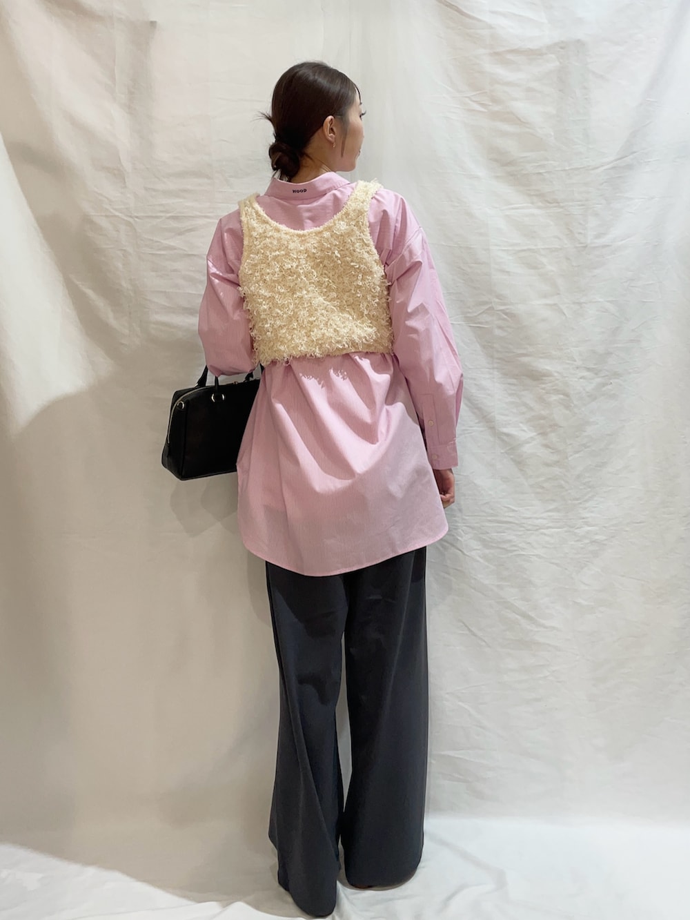 ブラック系のボストンバッグ、ホワイト系のベスト、ピンク系のシャツ/ブラウスを着用したレディースの春コーディネートの3枚目の写真