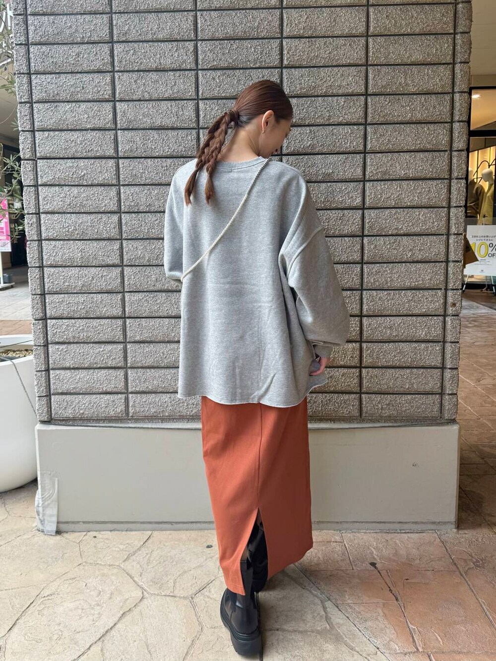 グレー系のスウェット、オレンジ系のスカートを着用したレディースの秋コーディネートの2枚目の写真