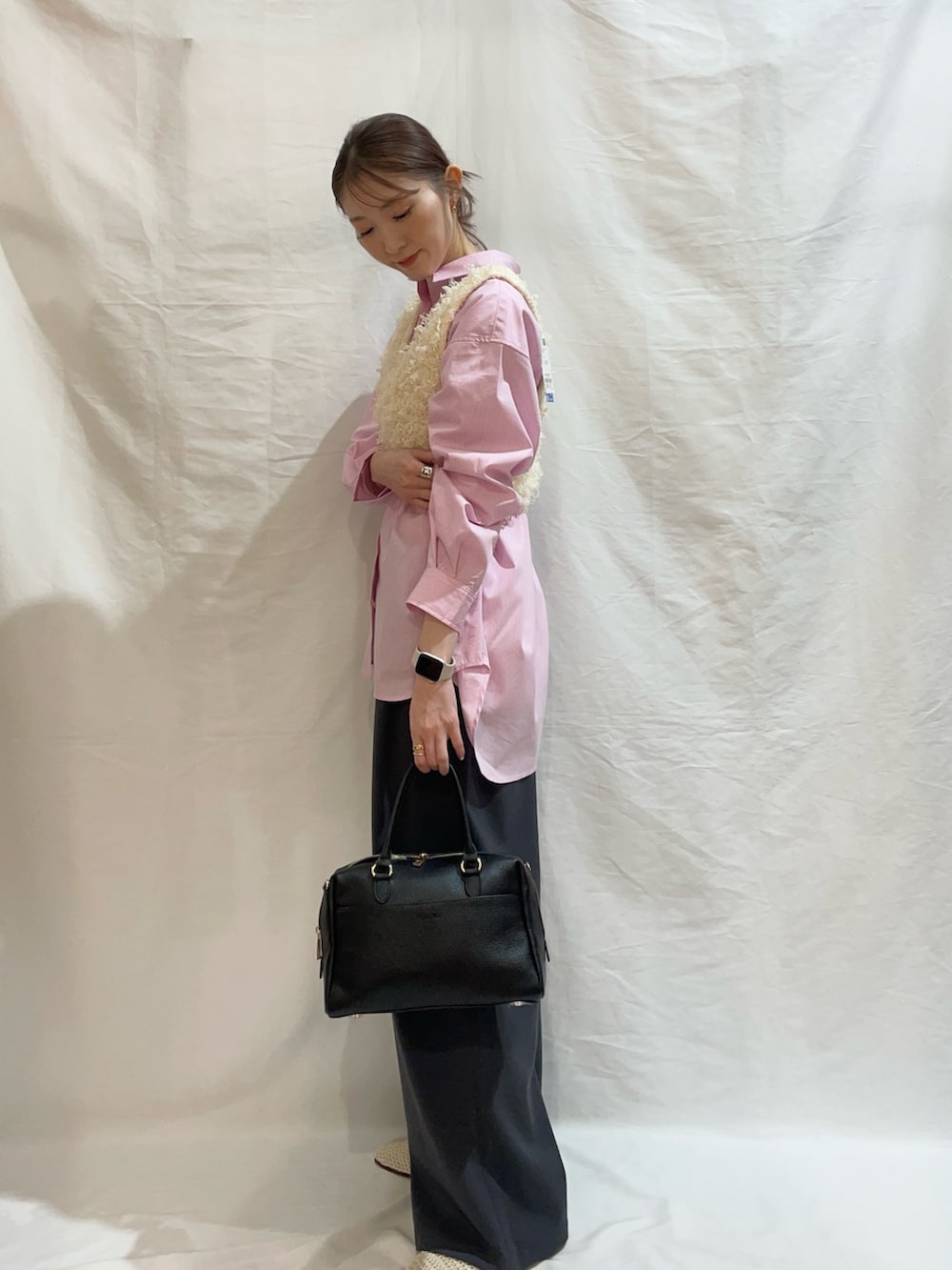 ブラック系のボストンバッグ、ホワイト系のベスト、ピンク系のシャツ/ブラウスを着用したレディースの春コーディネートの2枚目の写真