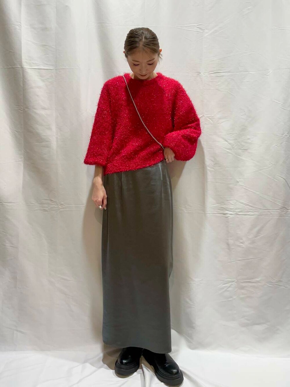 グレー系のスカート、レッド系のニット/セーターを着用したレディースの冬コーディネートの3枚目の写真