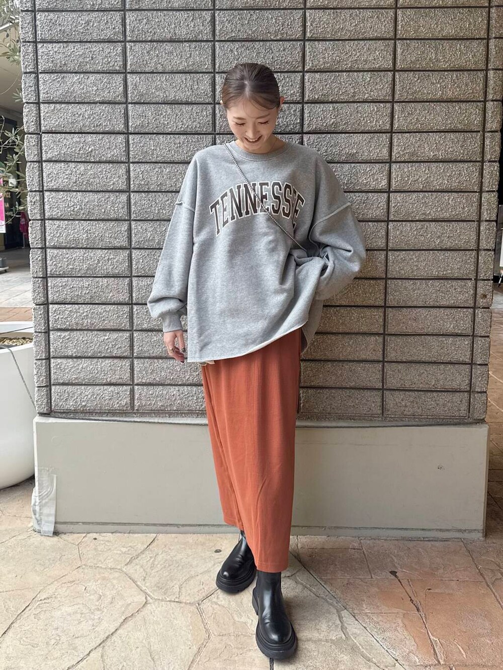 グレー系のスウェット、オレンジ系のスカートを着用したレディースの秋コーディネートの3枚目の写真