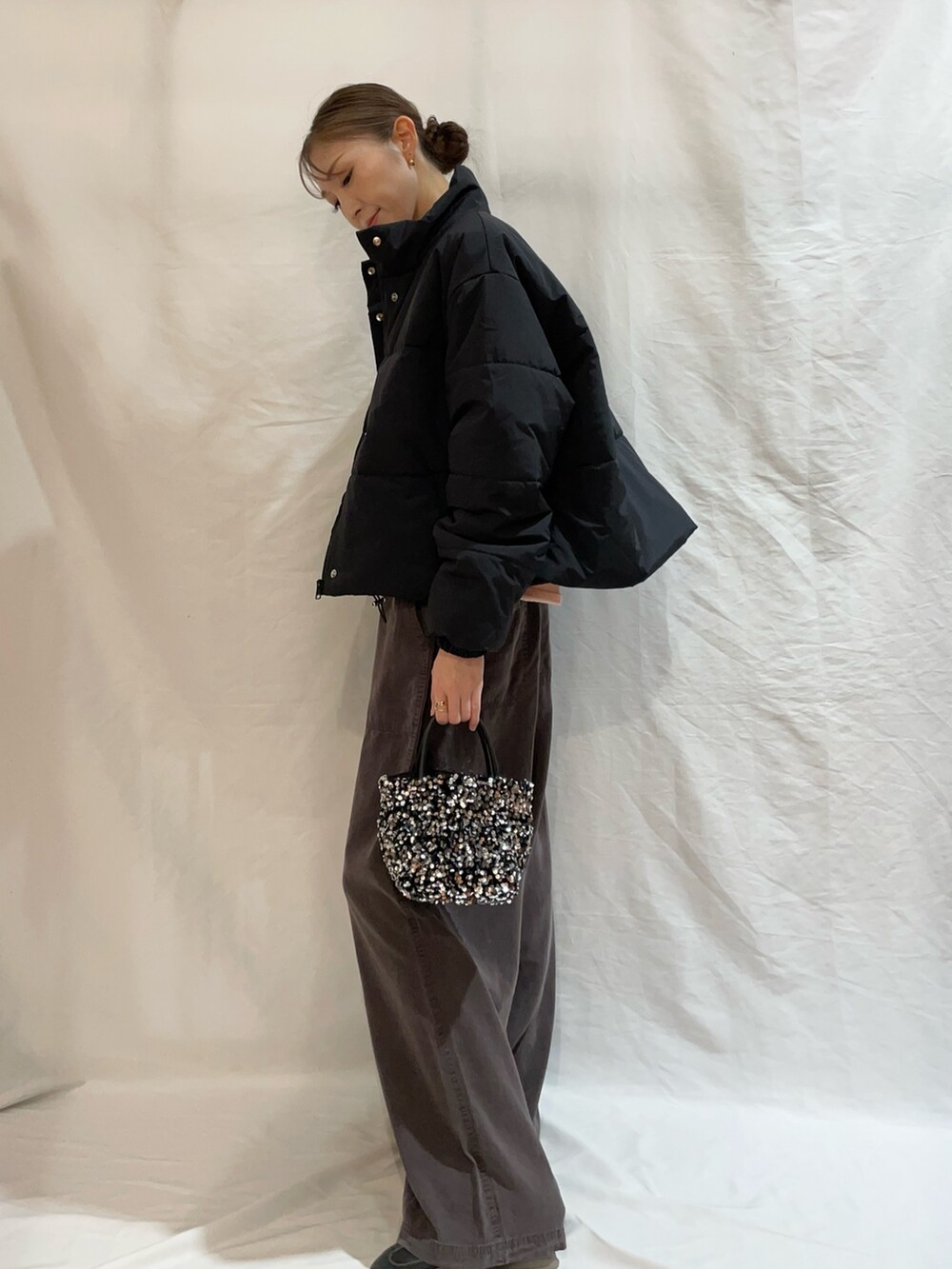 ピンク系のニット/セーター、ブラック系のダウンジャケット/コート、シルバー系のショルダーバッグを着用したレディースの秋コーディネートの3枚目の写真