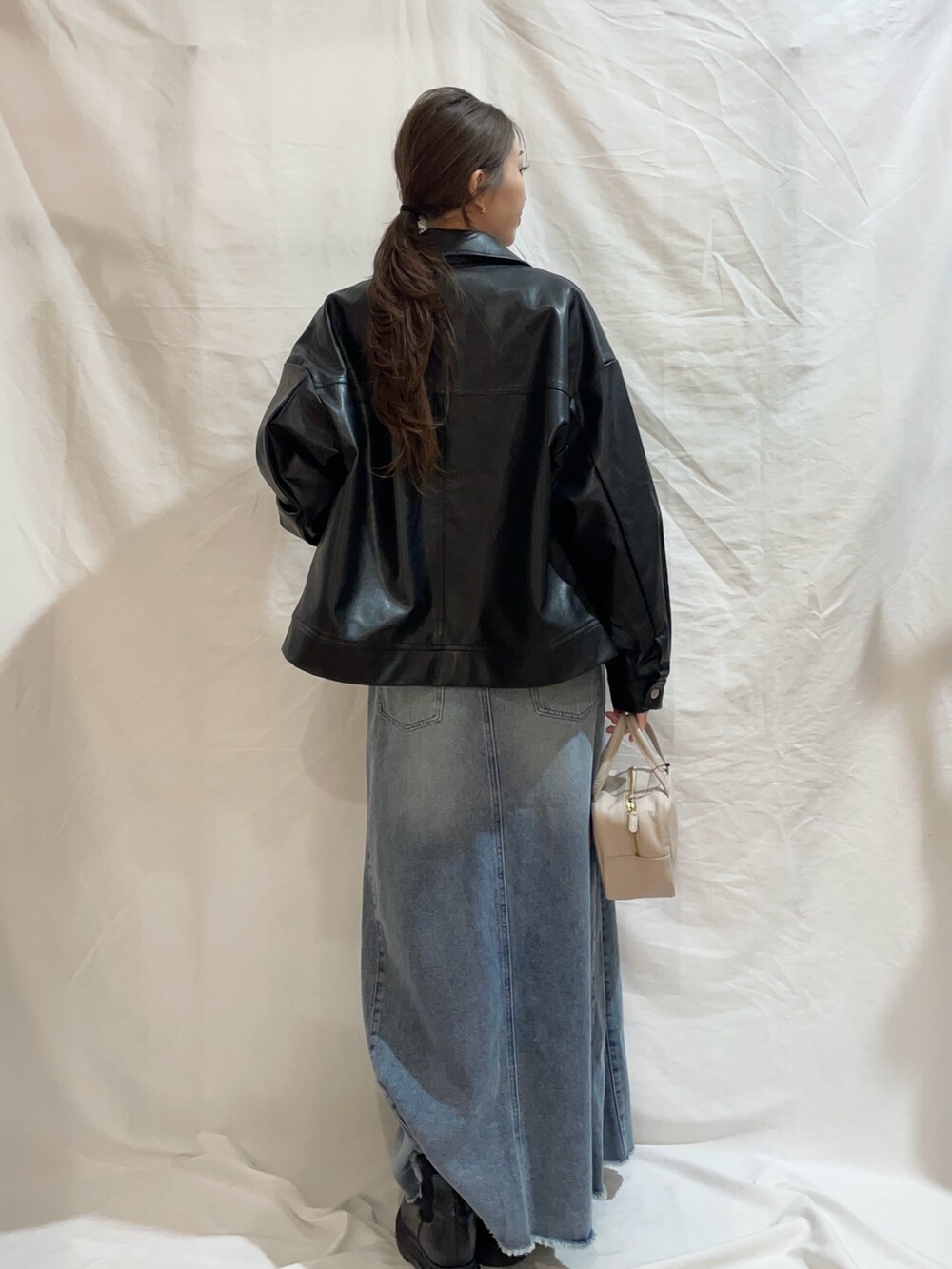 ブルー系のスカート、ピンク系のTシャツ/カットソー、ブラック系のブルゾンを着用したレディースの冬コーディネートの2枚目の写真