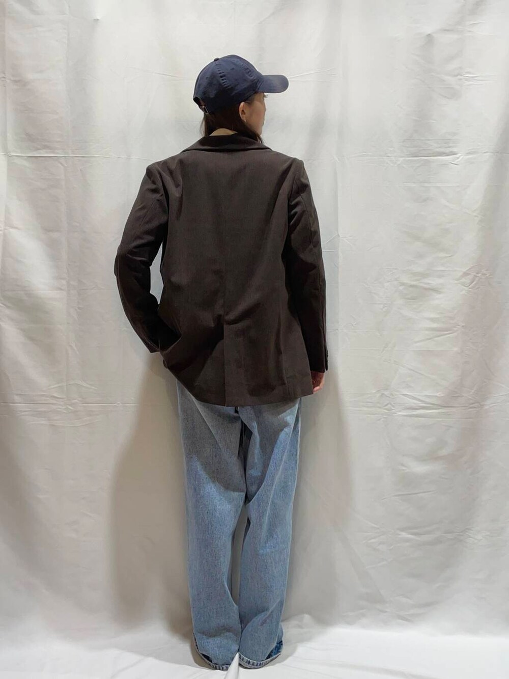 ブルー系のデニムパンツ、ブラウン系のその他アウター、ホワイト系のニット/セーターを着用したレディースの冬コーディネートの2枚目の写真