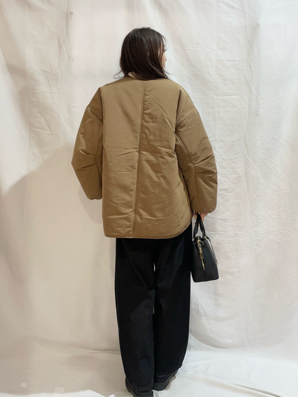 ホワイト系のニット/セーター、イエロー系のダウンジャケット/コート、ブラック系のデニムパンツを着用したレディースの冬コーディネートの4枚目の写真