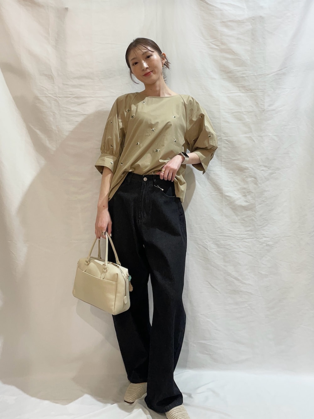 ブラック系のデニムパンツ、ベージュ系のシャツ/ブラウスを着用したレディースの春コーディネートの2枚目の写真