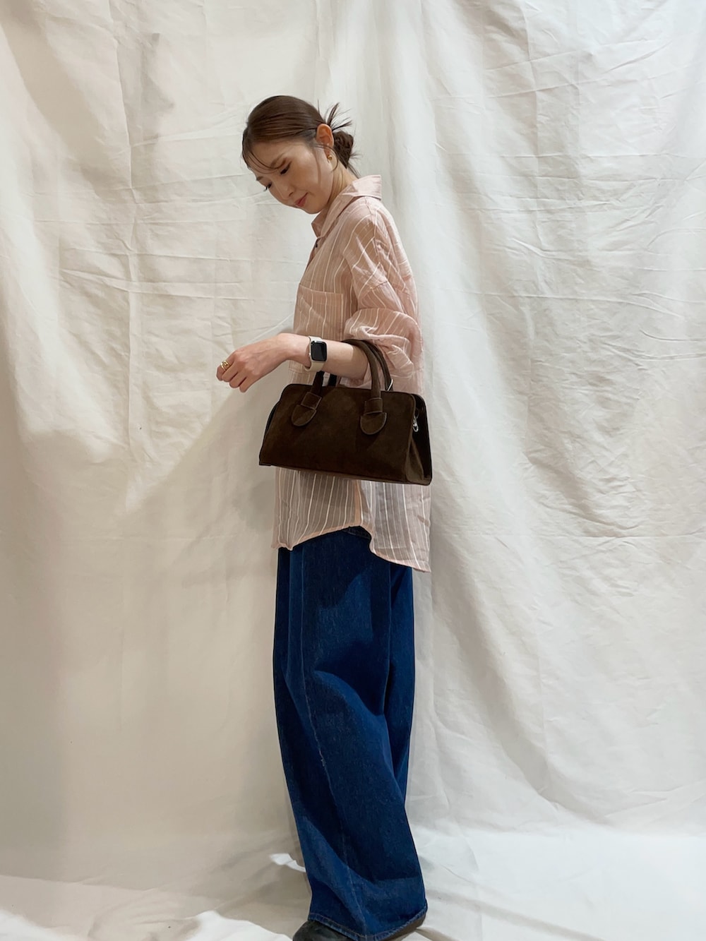 ブルー系のデニムパンツ、ブラウン系のボストンバッグ、ピンク系のシャツ/ブラウスを着用したレディースの夏コーディネートの2枚目の写真