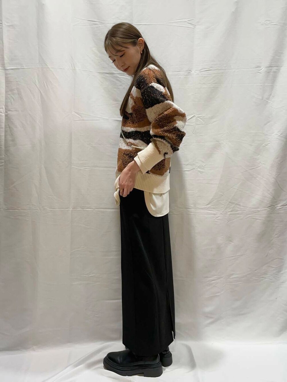 ホワイト系のニット/セーター、ブラック系のスカート、ホワイト系のTシャツ/カットソーを着用したレディースの冬コーディネートの2枚目の写真