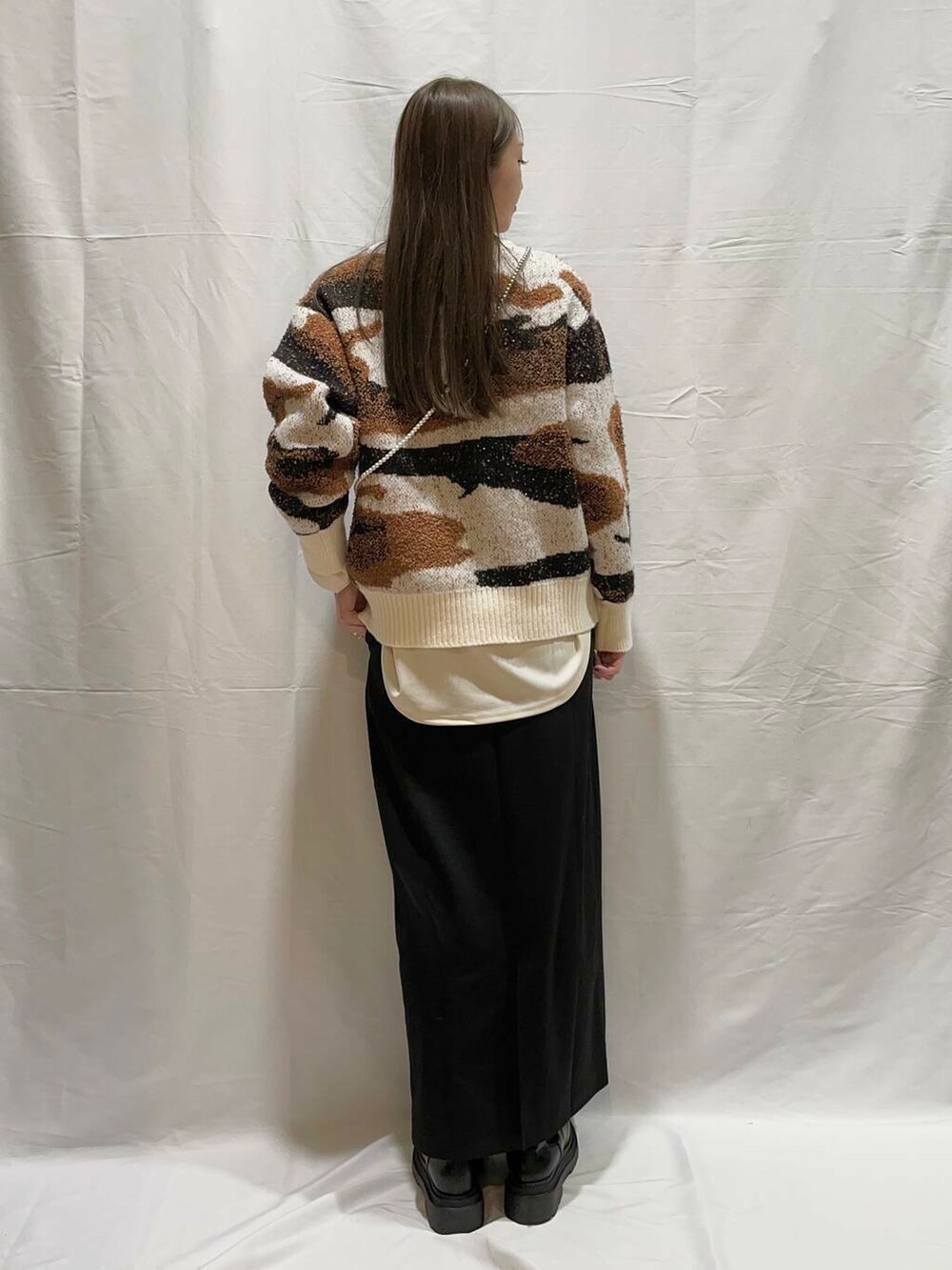 ホワイト系のニット/セーター、ブラック系のスカート、ホワイト系のTシャツ/カットソーを着用したレディースの冬コーディネートの3枚目の写真