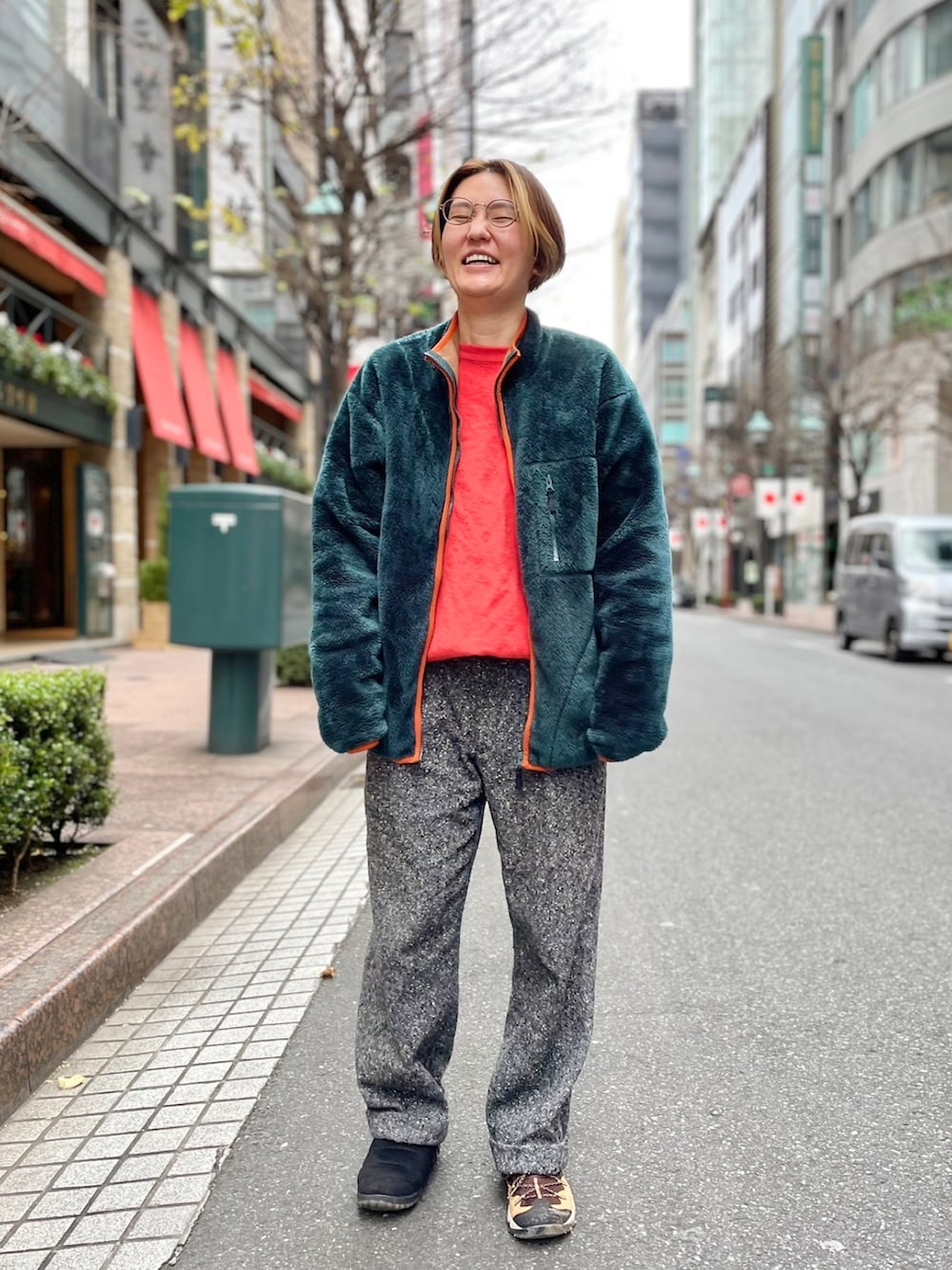 グレー系のスラックス、オレンジ系のニット/セーター、ホワイト系のダウンジャケット/コートを着用したレディースの冬コーディネートの2枚目の写真