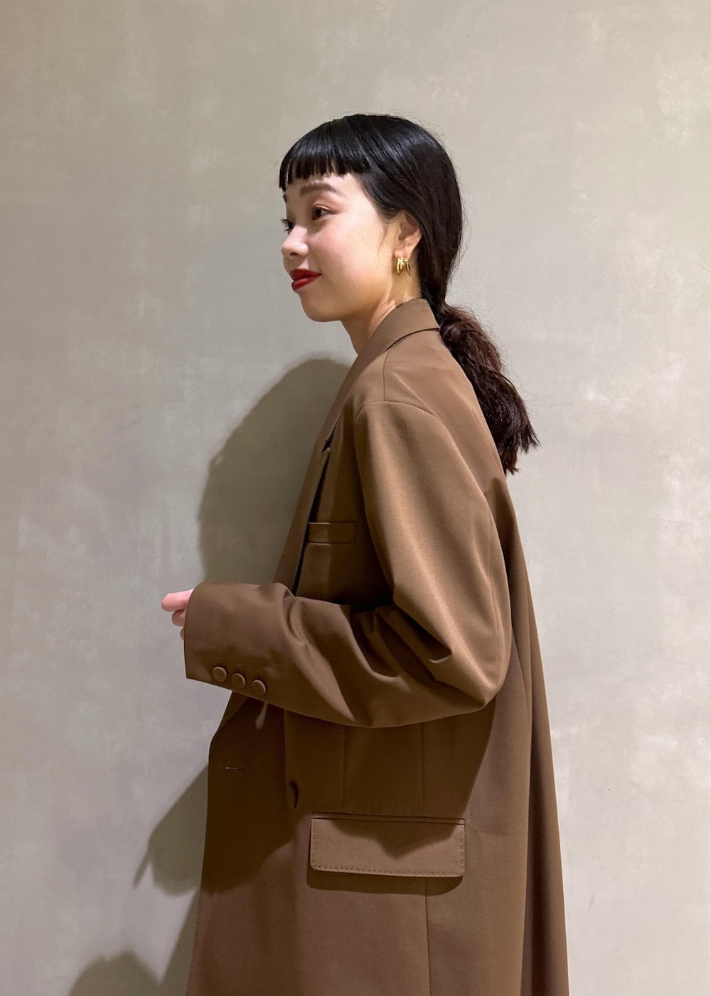 ブラック系のサンダル、ブラウン系のテーラードジャケット、ブルー系のシャツワンピースを着用したレディースの秋コーディネートの6枚目の写真