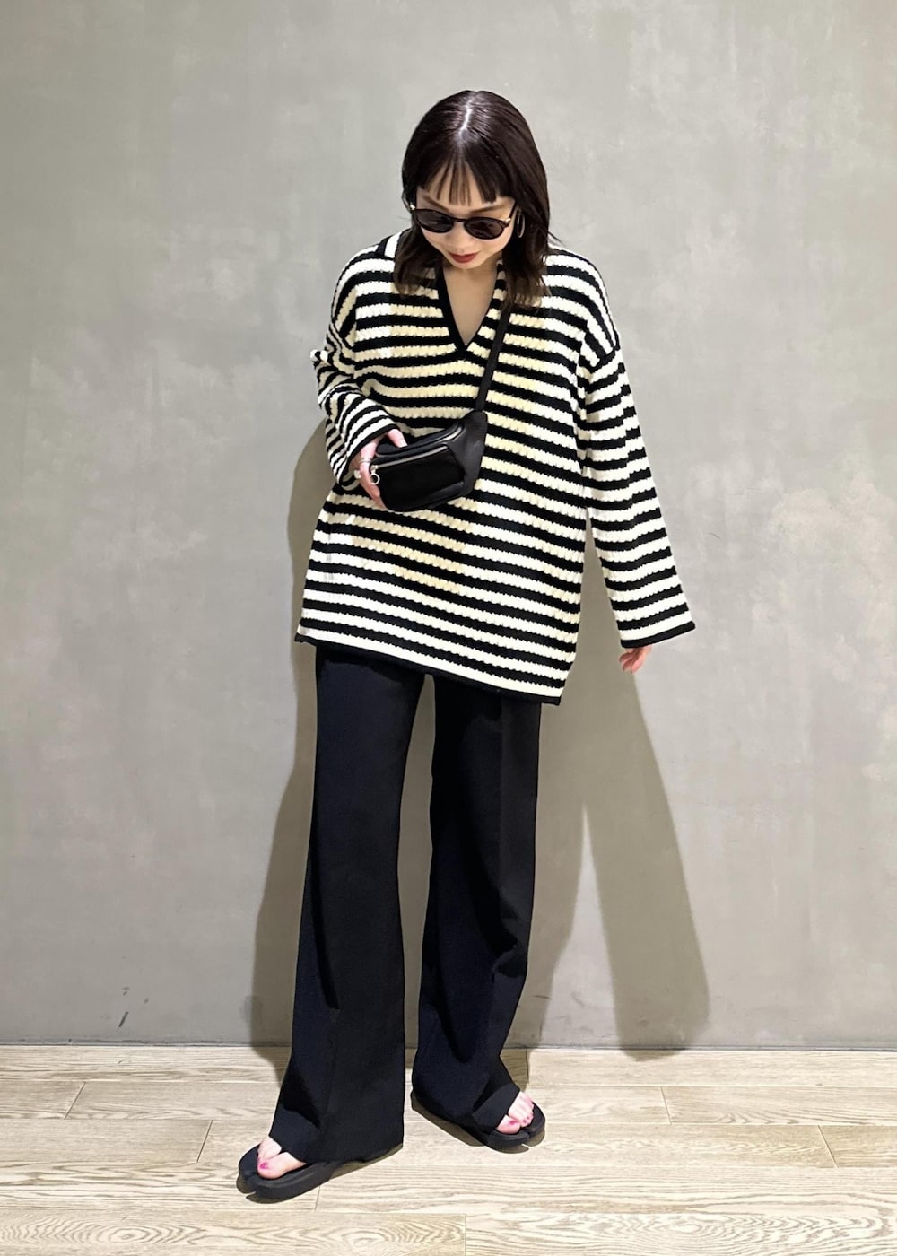 ブラック系のニット/セーター、ブラック系のスラックス、ブラック系のサンダルを着用したレディースの夏コーディネートの2枚目の写真