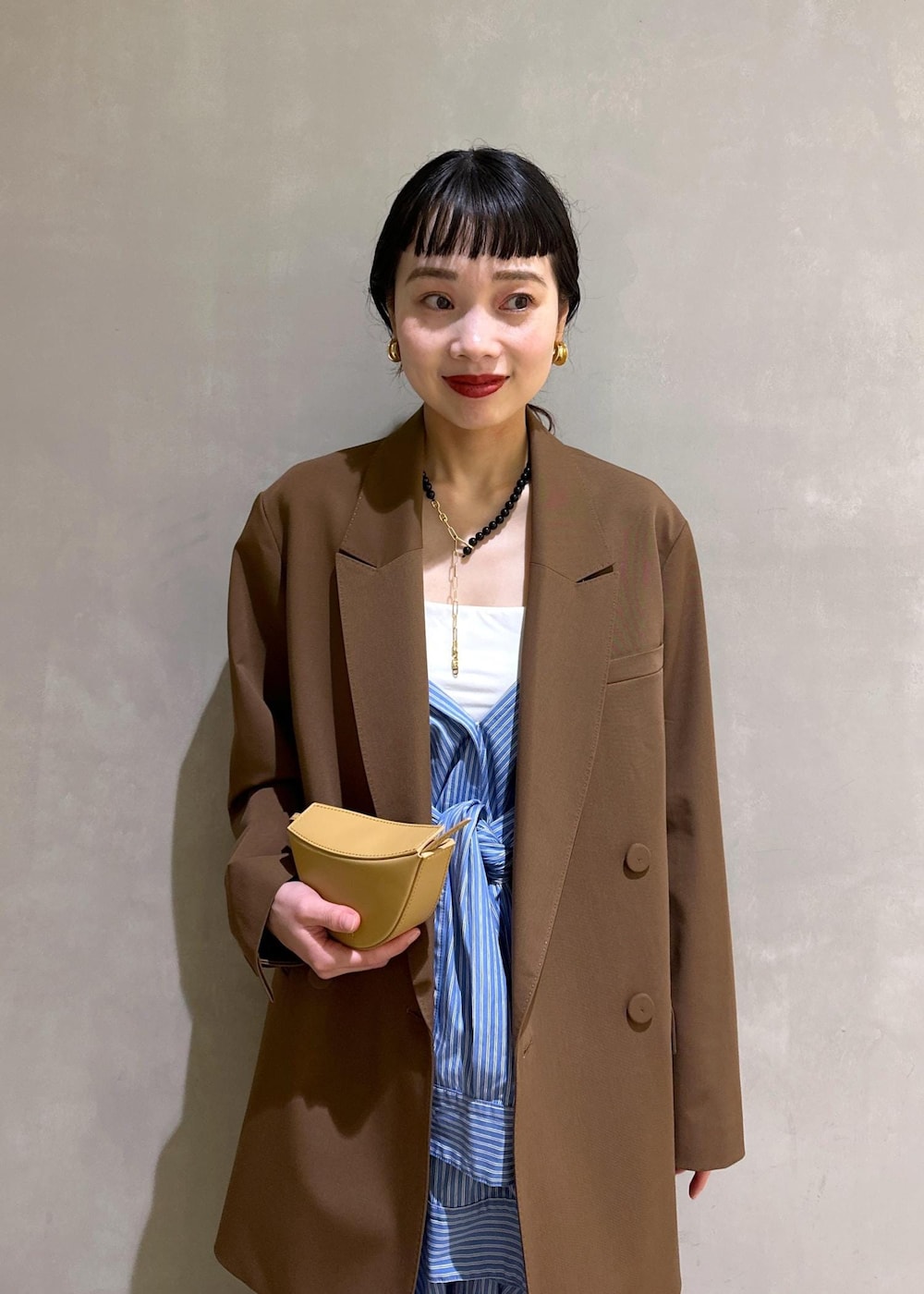 ブラック系のサンダル、ブラウン系のテーラードジャケット、ブルー系のシャツワンピースを着用したレディースの秋コーディネートの5枚目の写真