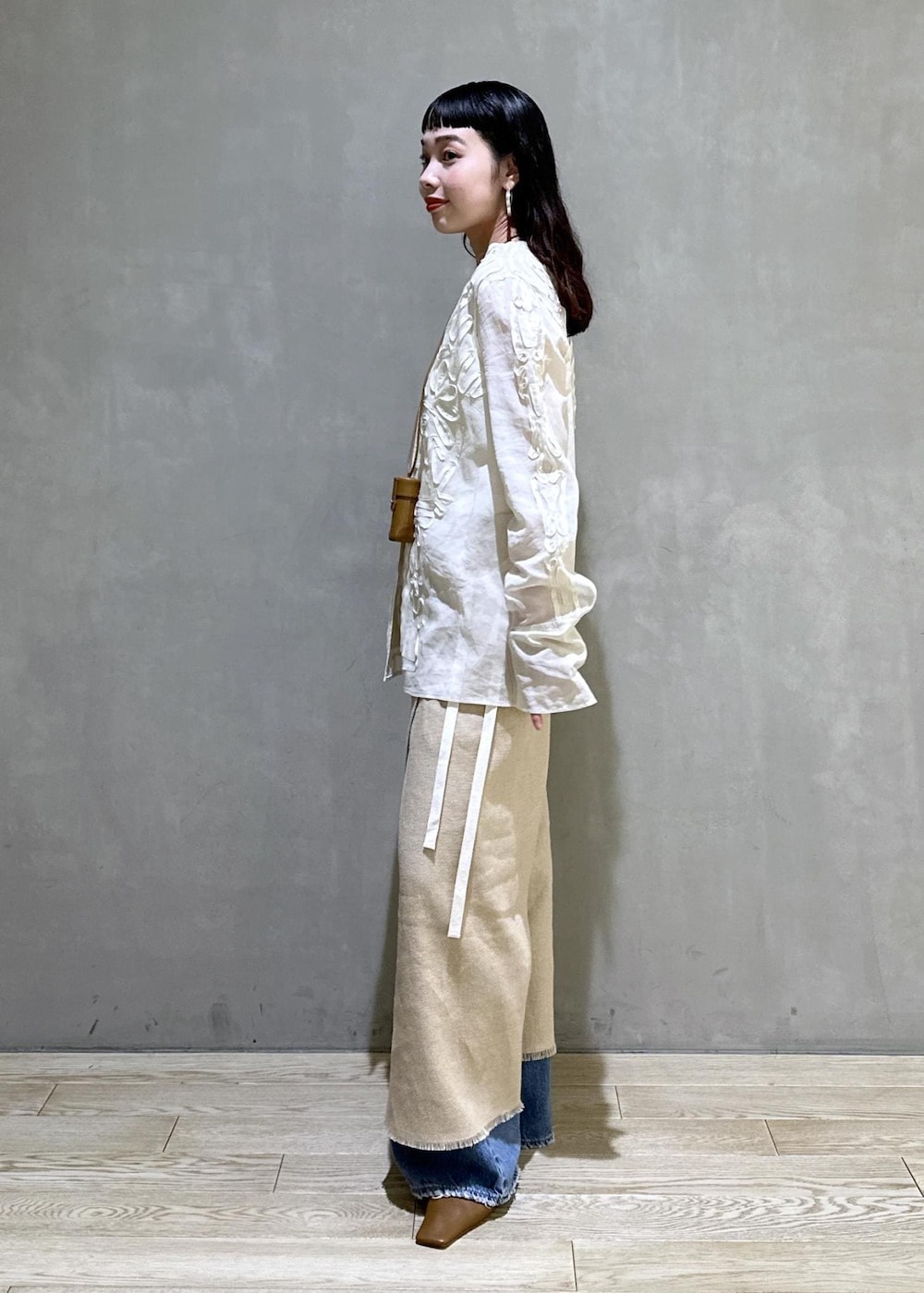 ベージュ系のスカート、ホワイト系のシャツ/ブラウス、ブルー系のデニムパンツを着用したレディースの冬コーディネートの3枚目の写真