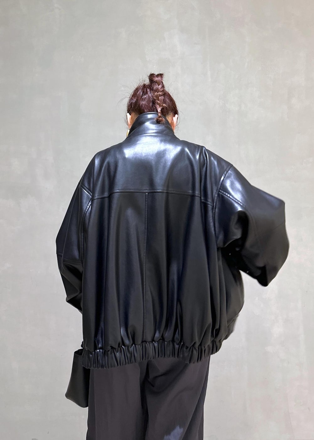 ブラック系のハンドバッグ、ブラック系のライダースジャケット、ブルー系のニット/セーターを着用したレディースの秋コーディネートの7枚目の写真