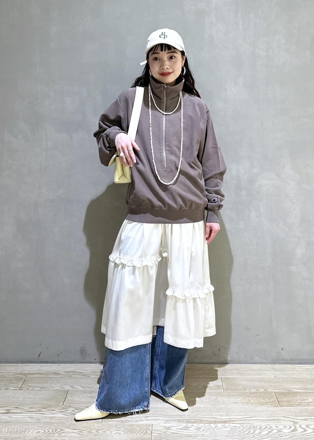 ホワイト系のスカート、ブラウン系のスウェット、ベージュ系のサンダルを着用したレディースの冬コーディネートの2枚目の写真