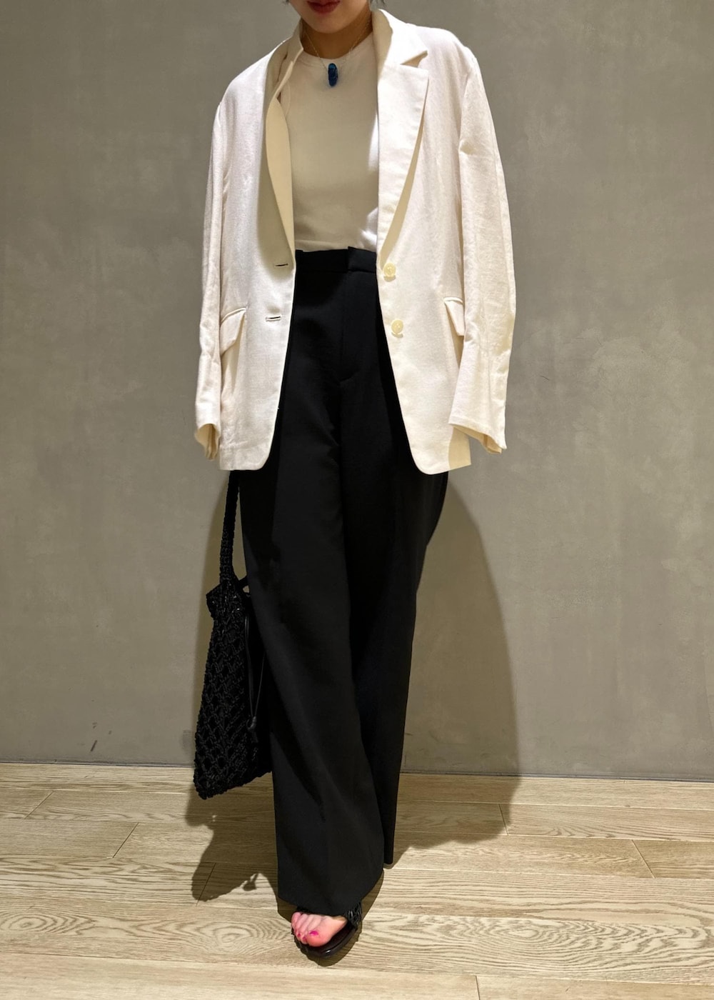 ホワイト系のタンクトップ、ホワイト系のテーラードジャケット、ブラック系のハンドバッグを着用したレディースの夏コーディネートの6枚目の写真