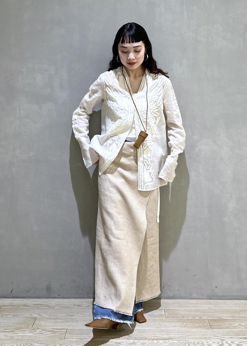 ベージュ系のスカート、ホワイト系のシャツ/ブラウス、ブルー系のデニムパンツを着用したレディースの冬コーディネートの2枚目の写真