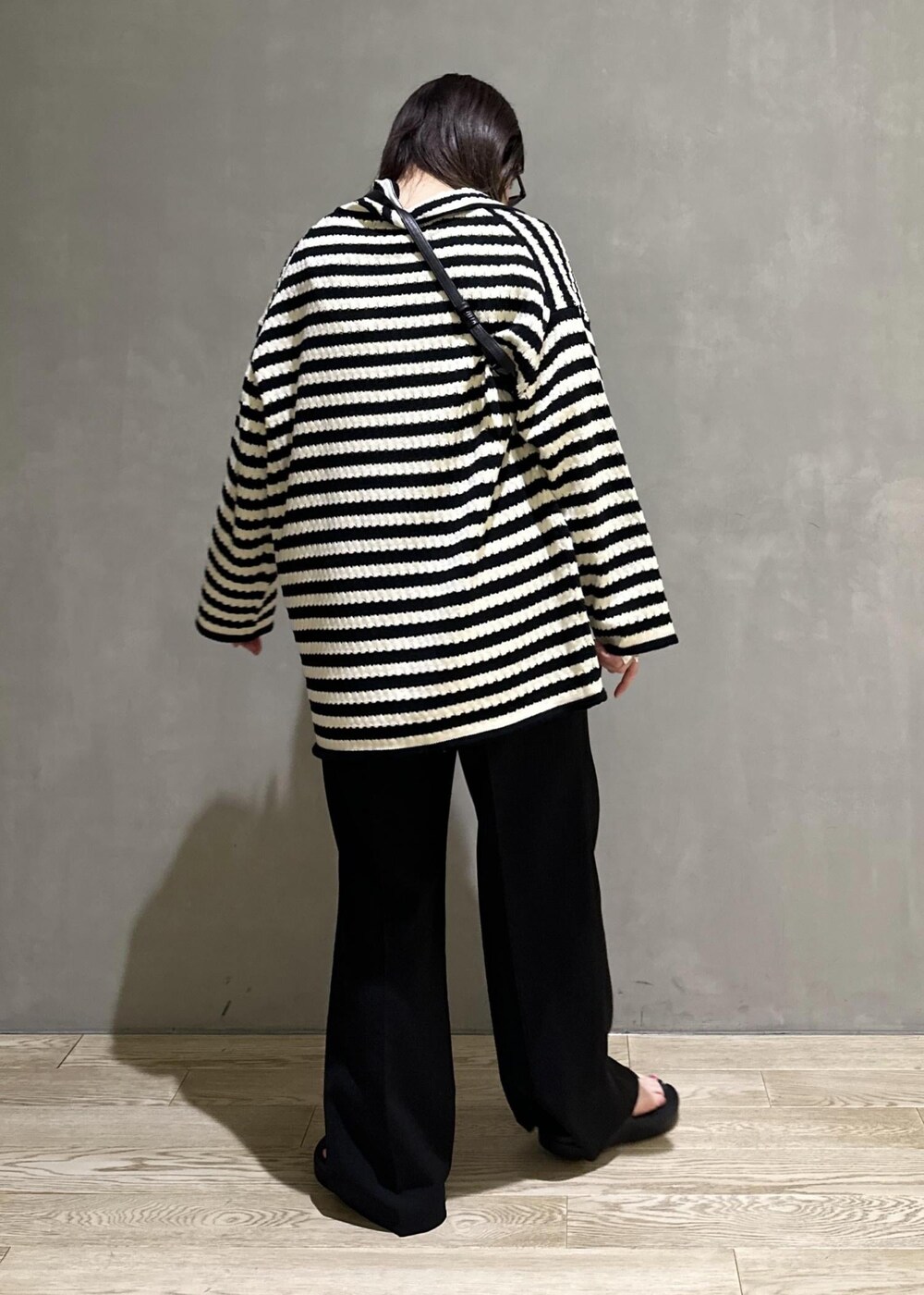 ブラック系のニット/セーター、ブラック系のスラックス、ブラック系のサンダルを着用したレディースの夏コーディネートの3枚目の写真