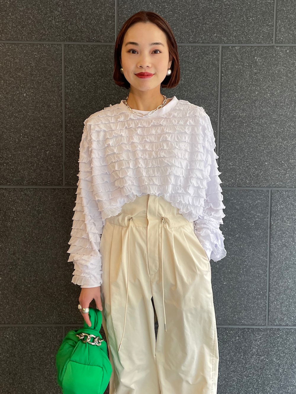 ホワイト系のTシャツ/カットソー、ホワイト系のパンツ、グリーン系のハンドバッグを着用したレディースの冬コーディネートの3枚目の写真