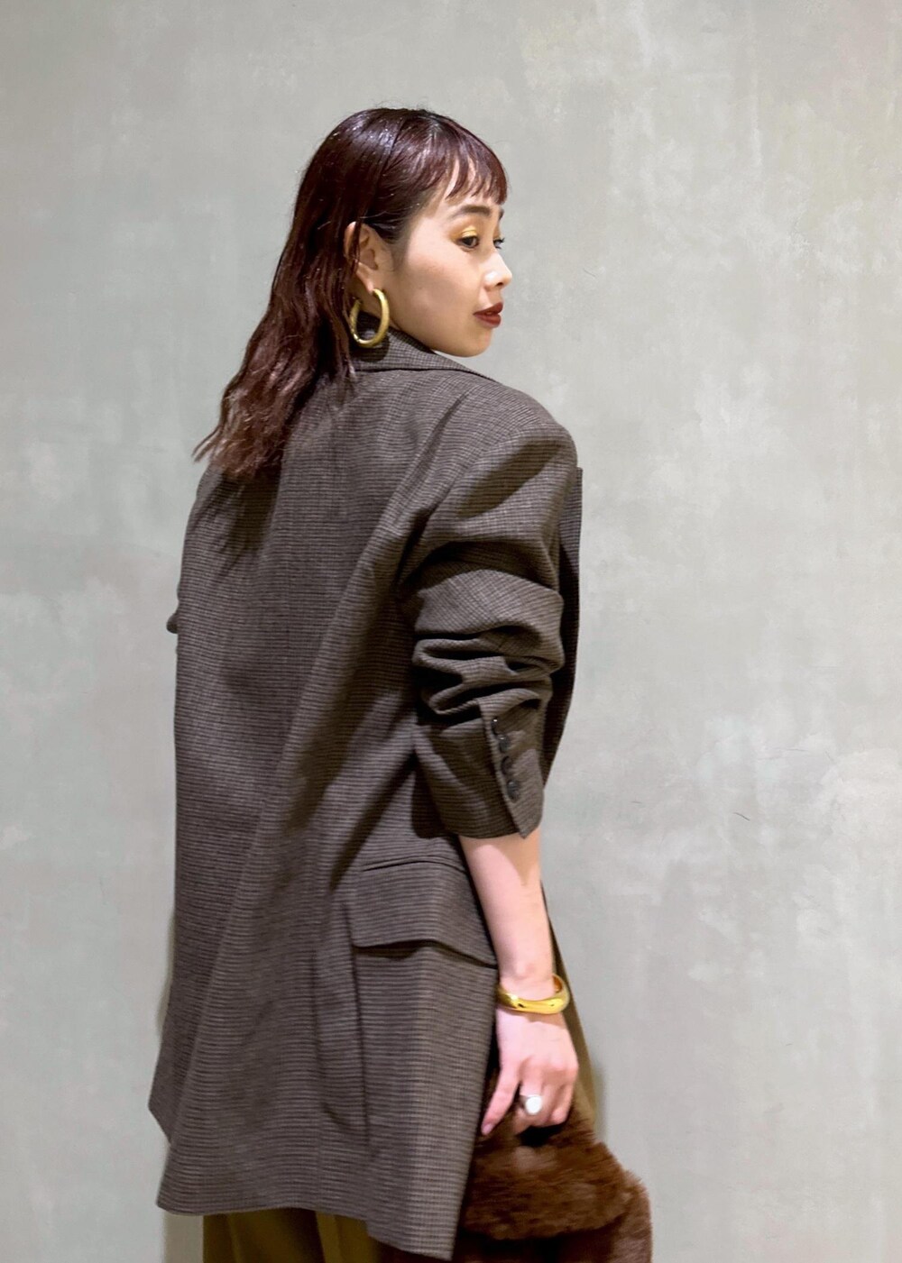 ブラウン系のスラックス、ブラック系のパンプス、ブラウン系のトートバッグを着用したレディースの秋コーディネートの7枚目の写真