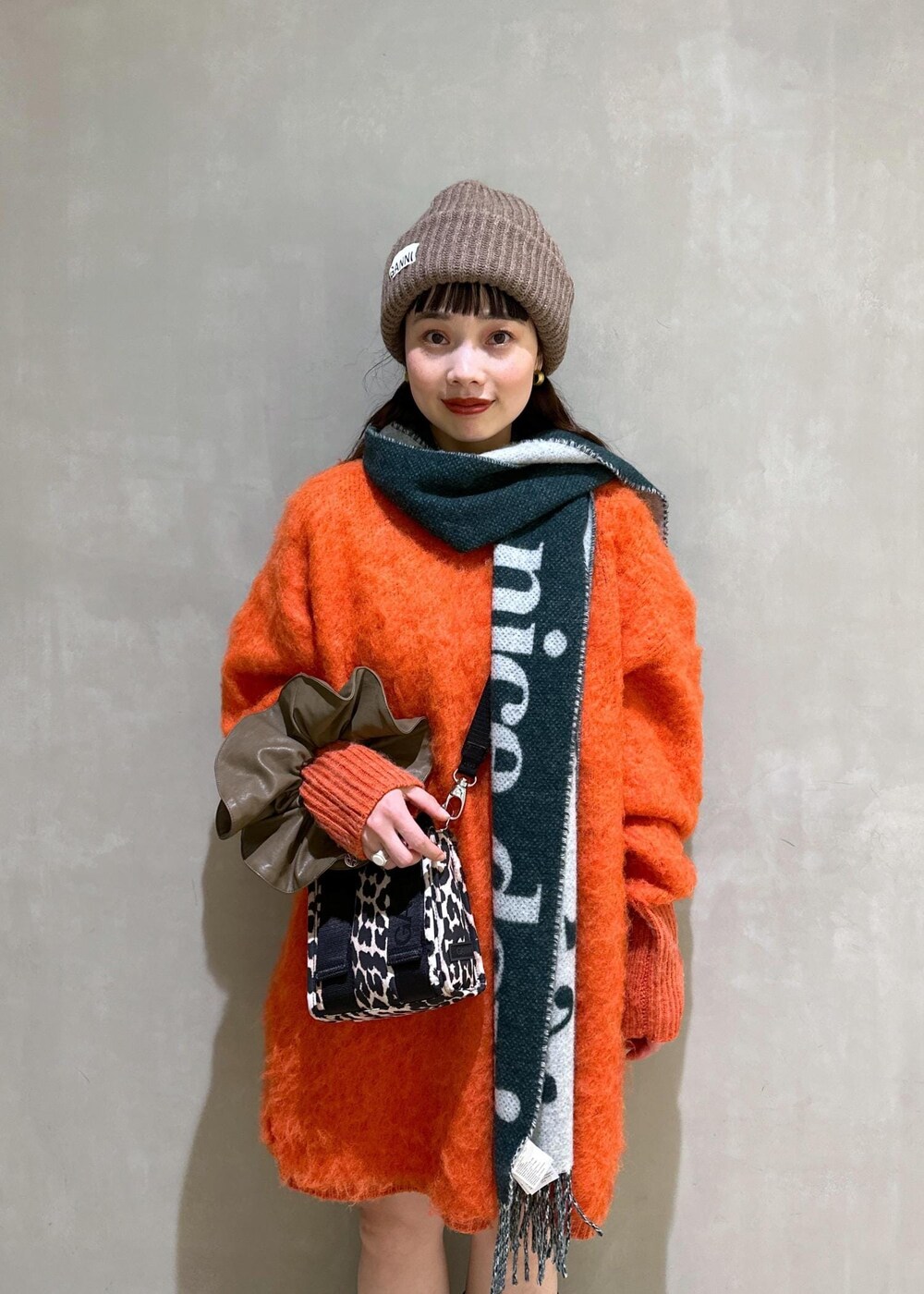 ベージュ系のトートバッグ、オレンジ系のワンピース、ブラウン系のシュシュを着用したレディースの秋コーディネートの6枚目の写真