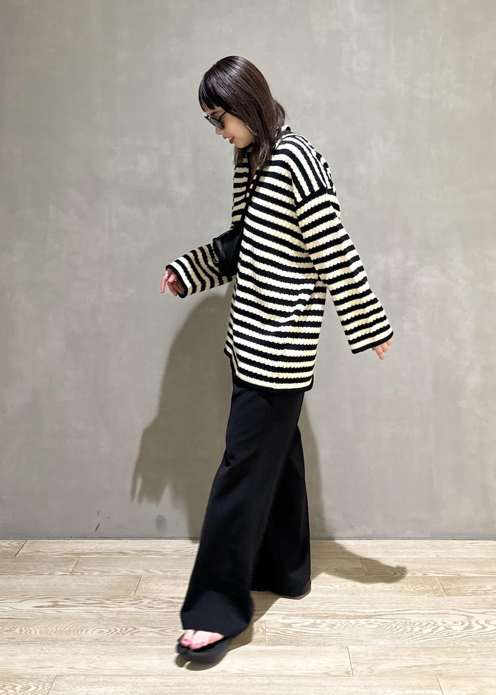 ブラック系のニット/セーター、ブラック系のスラックス、ブラック系のサンダルを着用したレディースの夏コーディネートの4枚目の写真