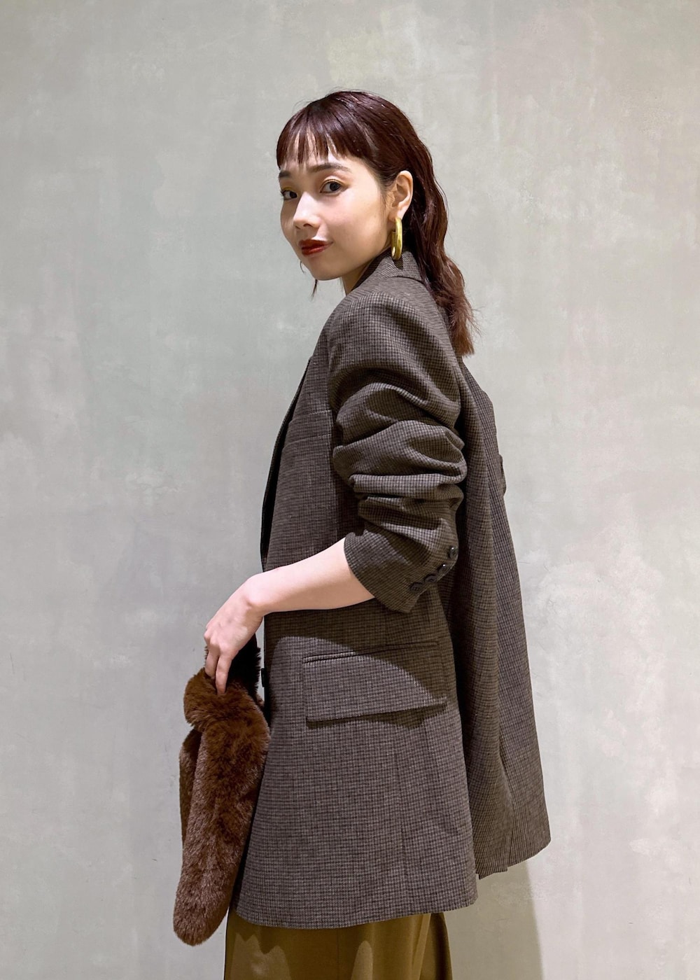 ブラウン系のスラックス、ブラック系のパンプス、ブラウン系のトートバッグを着用したレディースの秋コーディネートの6枚目の写真