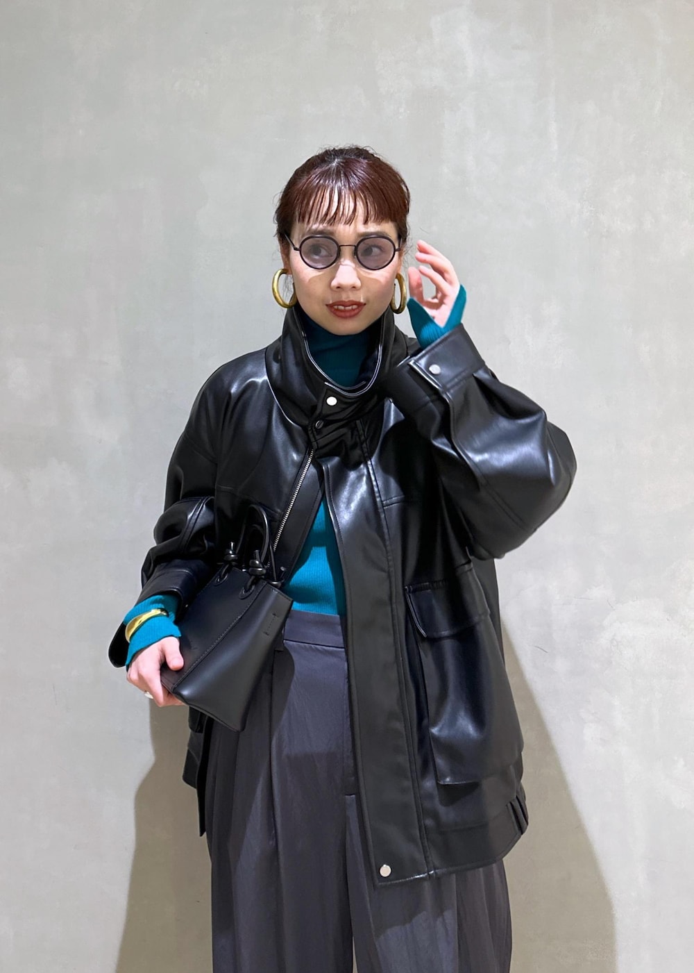 ブラック系のハンドバッグ、ブラック系のライダースジャケット、ブルー系のニット/セーターを着用したレディースの秋コーディネートの5枚目の写真