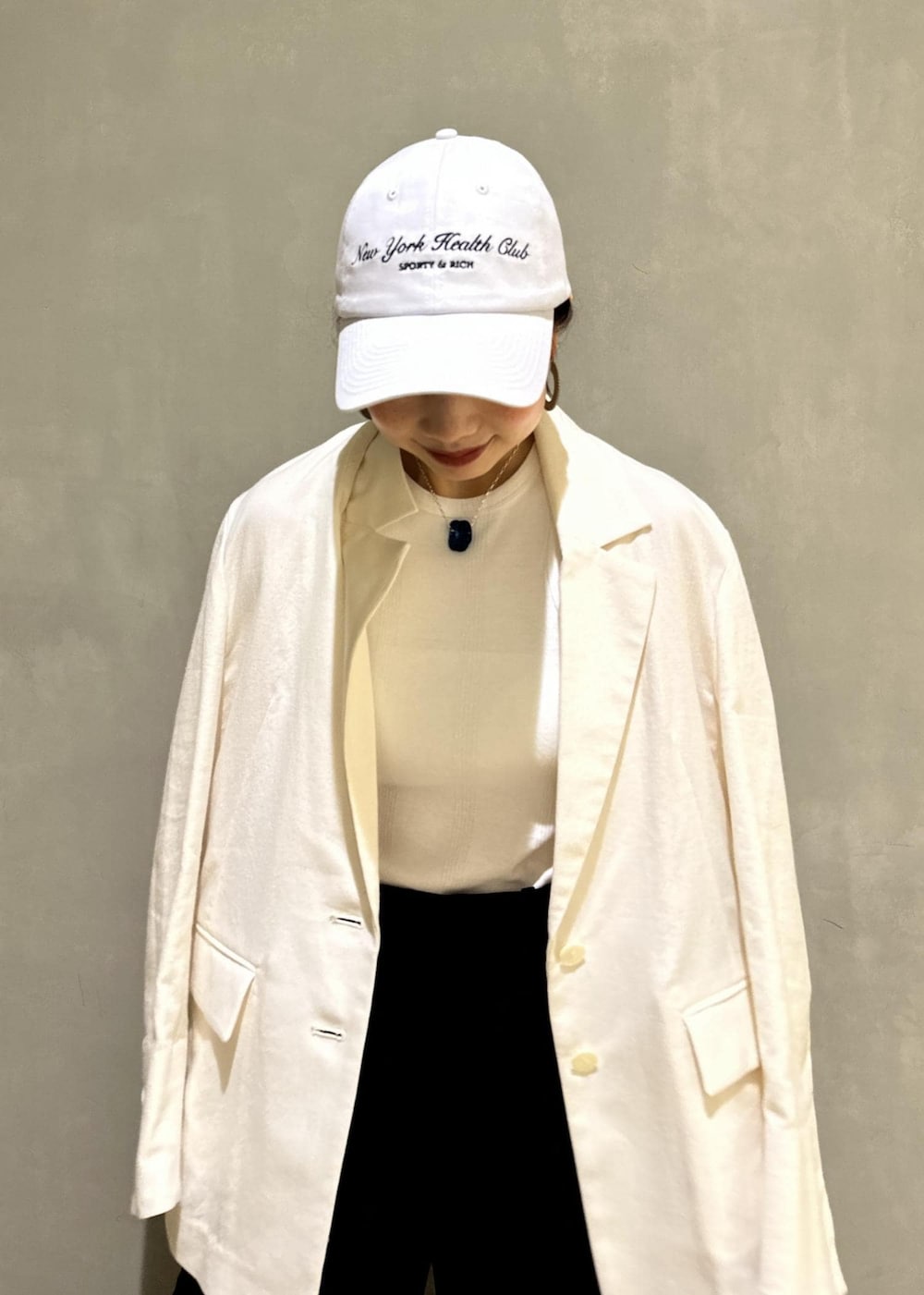 ホワイト系のタンクトップ、ホワイト系のテーラードジャケット、ブラック系のハンドバッグを着用したレディースの夏コーディネートの4枚目の写真