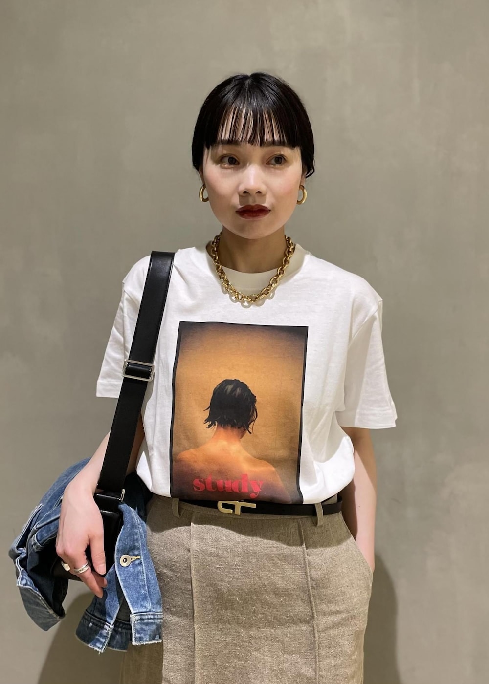 ブルー系のデニムジャケット、ブラック系のショルダーバッグ、ブラック系のサンダルを着用したレディースの春コーディネートの4枚目の写真