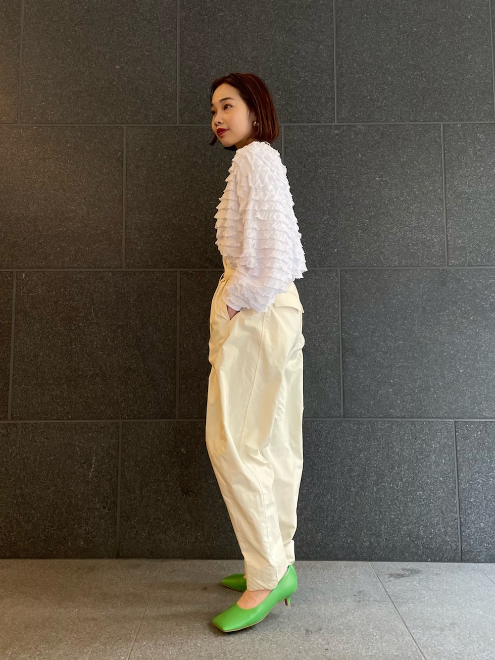 ホワイト系のTシャツ/カットソー、ホワイト系のパンツ、グリーン系のハンドバッグを着用したレディースの冬コーディネートの2枚目の写真