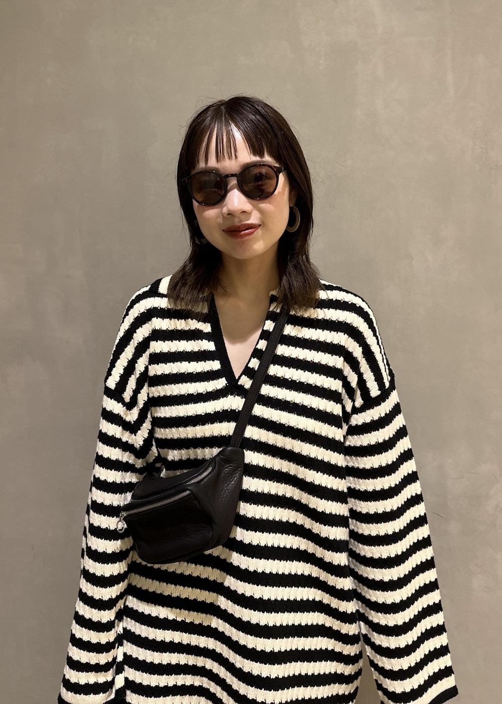 ブラック系のニット/セーター、ブラック系のスラックス、ブラック系のサンダルを着用したレディースの夏コーディネートの5枚目の写真