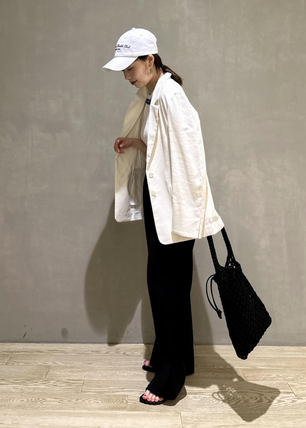 ホワイト系のタンクトップ、ホワイト系のテーラードジャケット、ブラック系のハンドバッグを着用したレディースの夏コーディネートの2枚目の写真