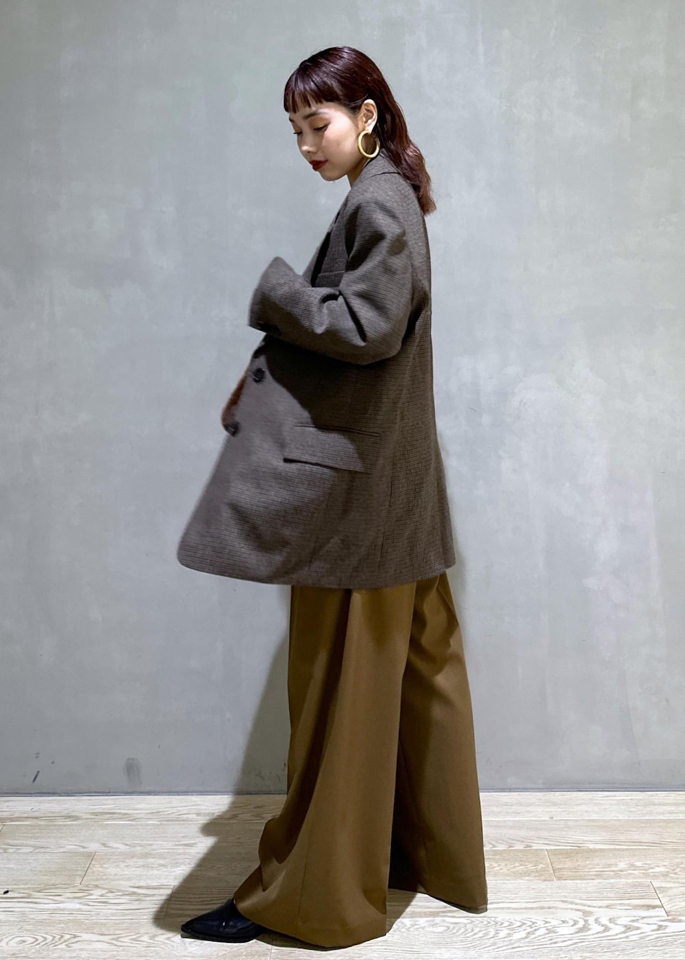 ブラウン系のスラックス、ブラック系のパンプス、ブラウン系のトートバッグを着用したレディースの秋コーディネートの4枚目の写真