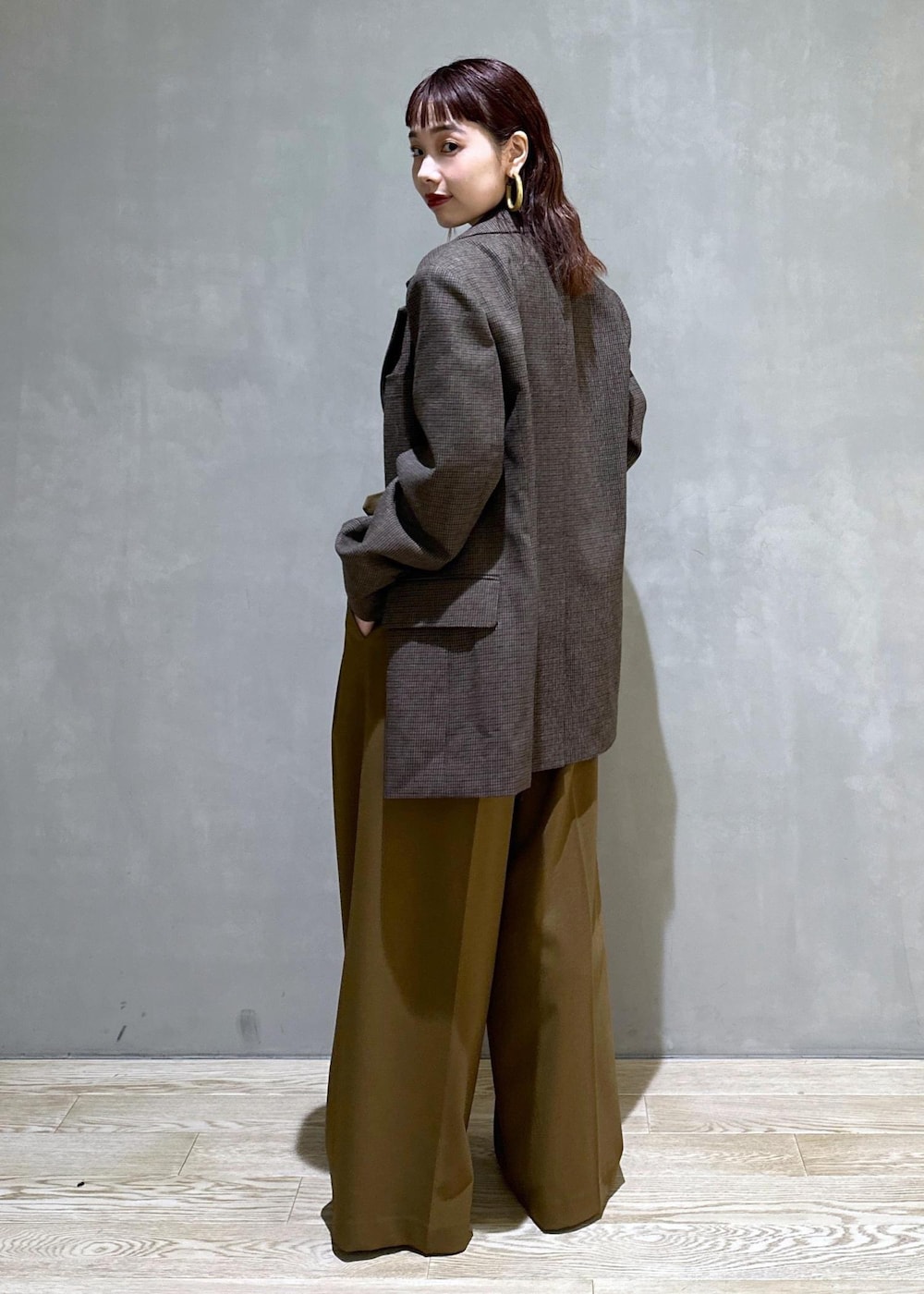 ブラウン系のスラックス、ブラック系のパンプス、ブラウン系のトートバッグを着用したレディースの秋コーディネートの3枚目の写真