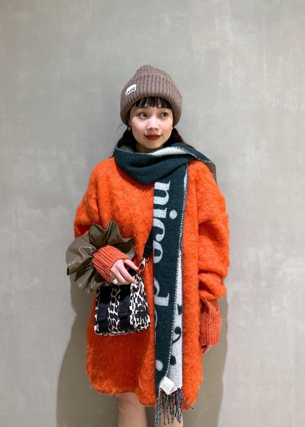 ベージュ系のトートバッグ、オレンジ系のワンピース、ブラウン系のシュシュを着用したレディースの秋コーディネートの8枚目の写真