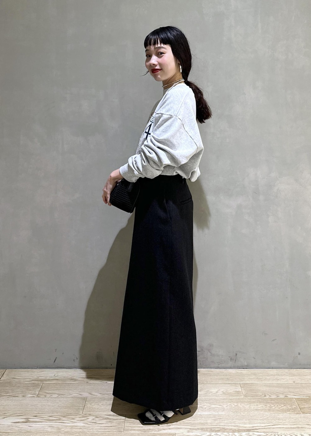 ブラック系のハンドバッグ、ブラック系のスカートを着用したレディースの秋コーディネートの2枚目の写真